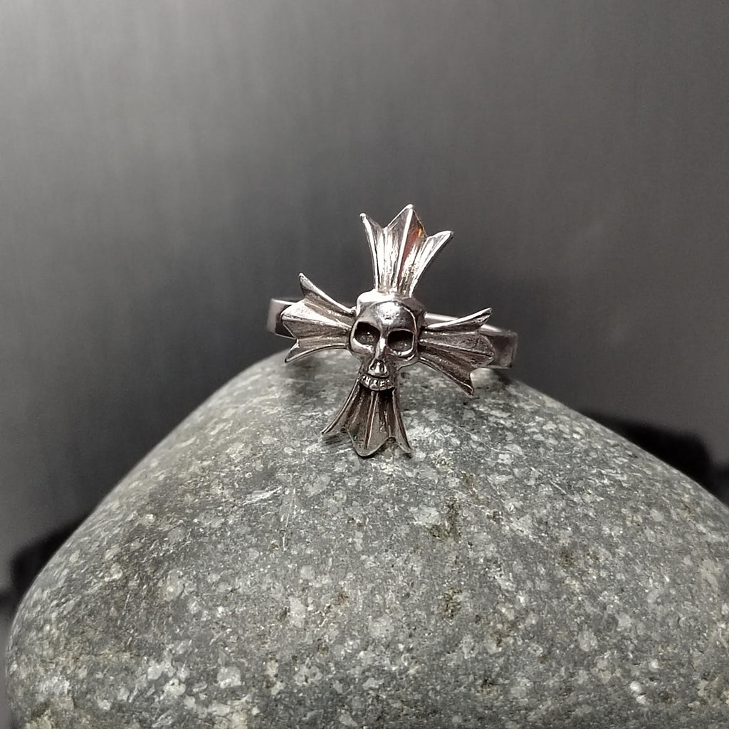 Silver skull and crossbones ring on a gray stone with a dark background