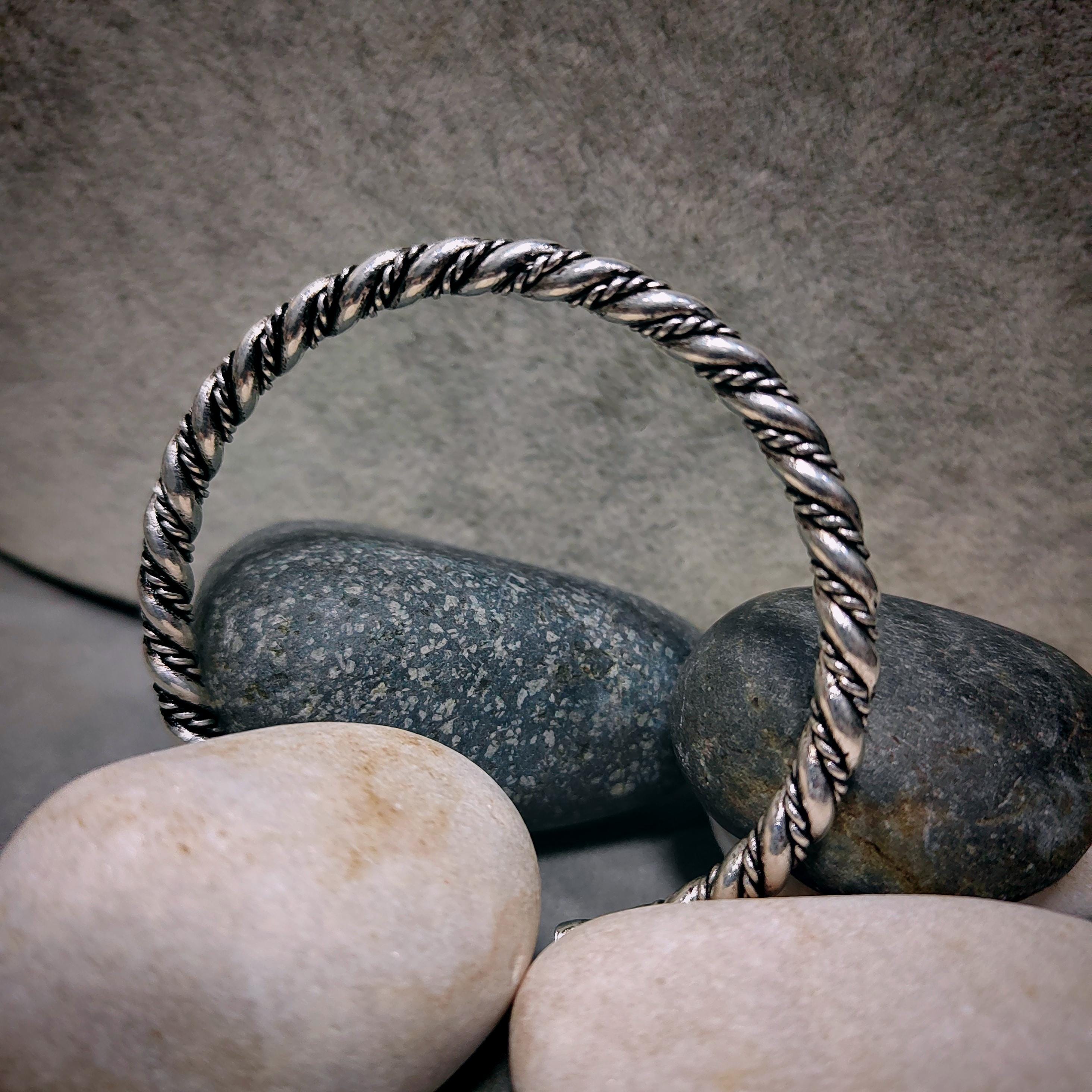 Silver twisted ring on stones with a neutral background