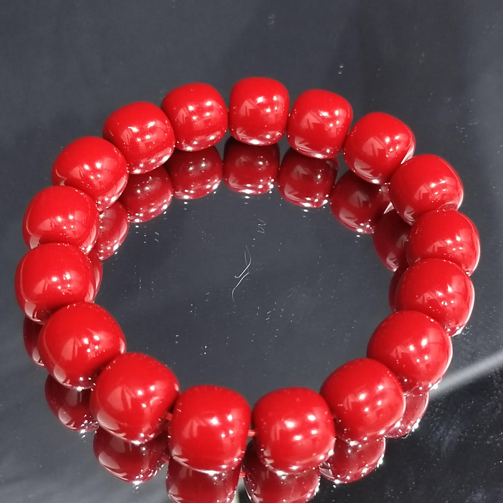 Red beaded bracelet on a reflective black surface