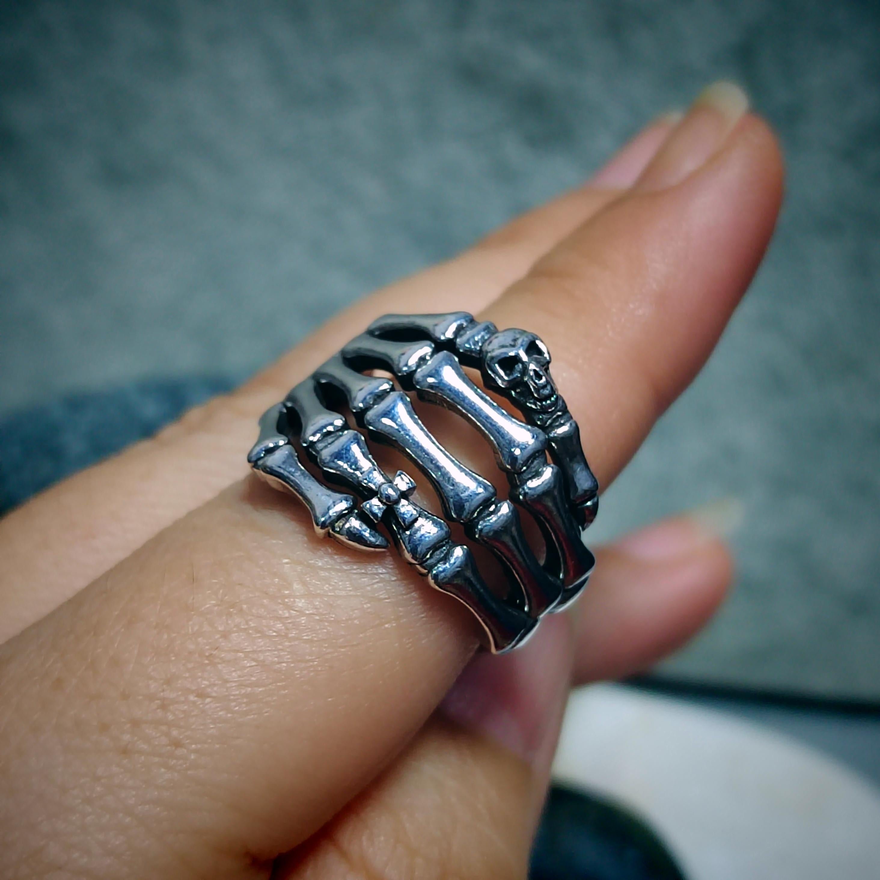 Silver skeleton ring on a finger with a blurred background