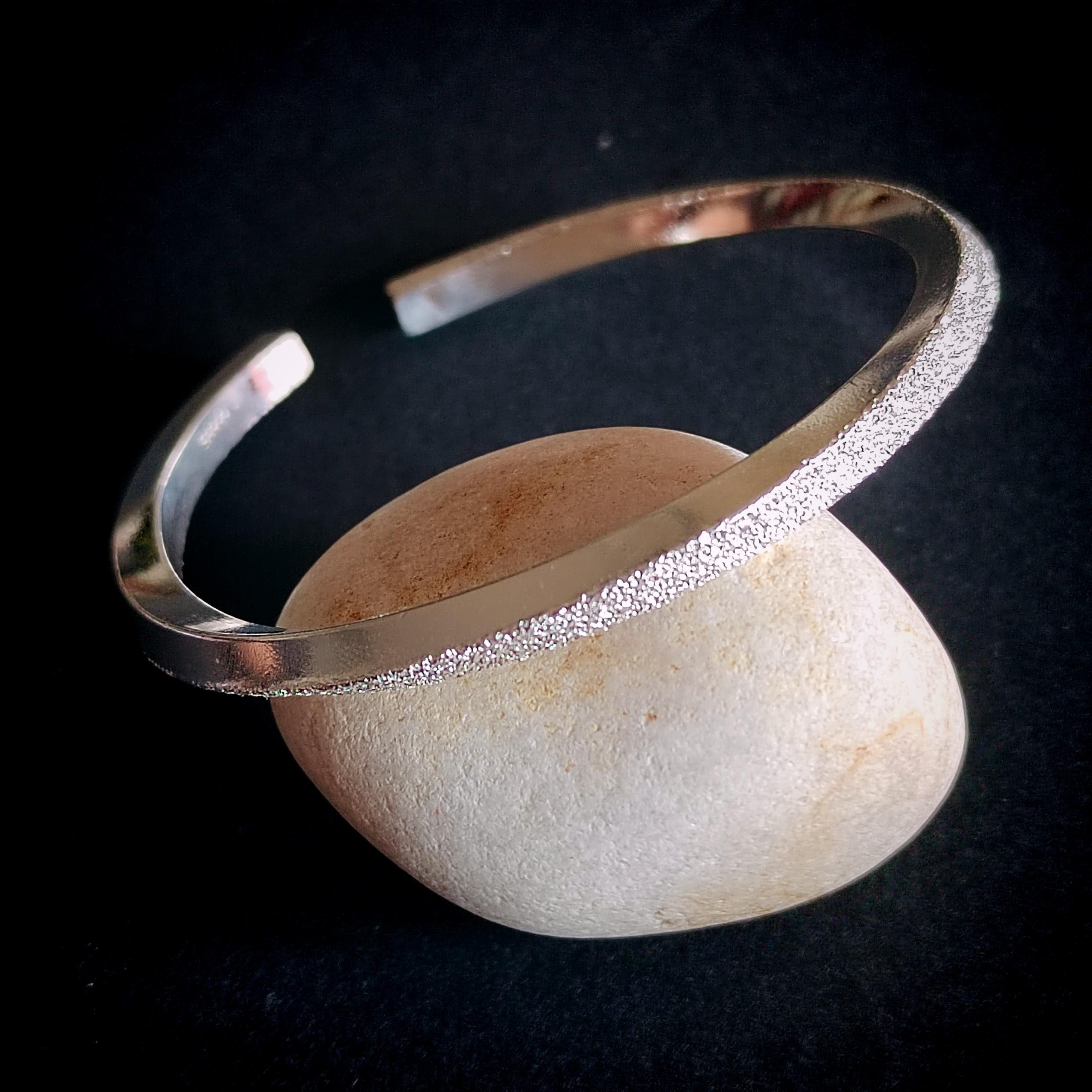 Silver bracelet on a stone surface with a dark background