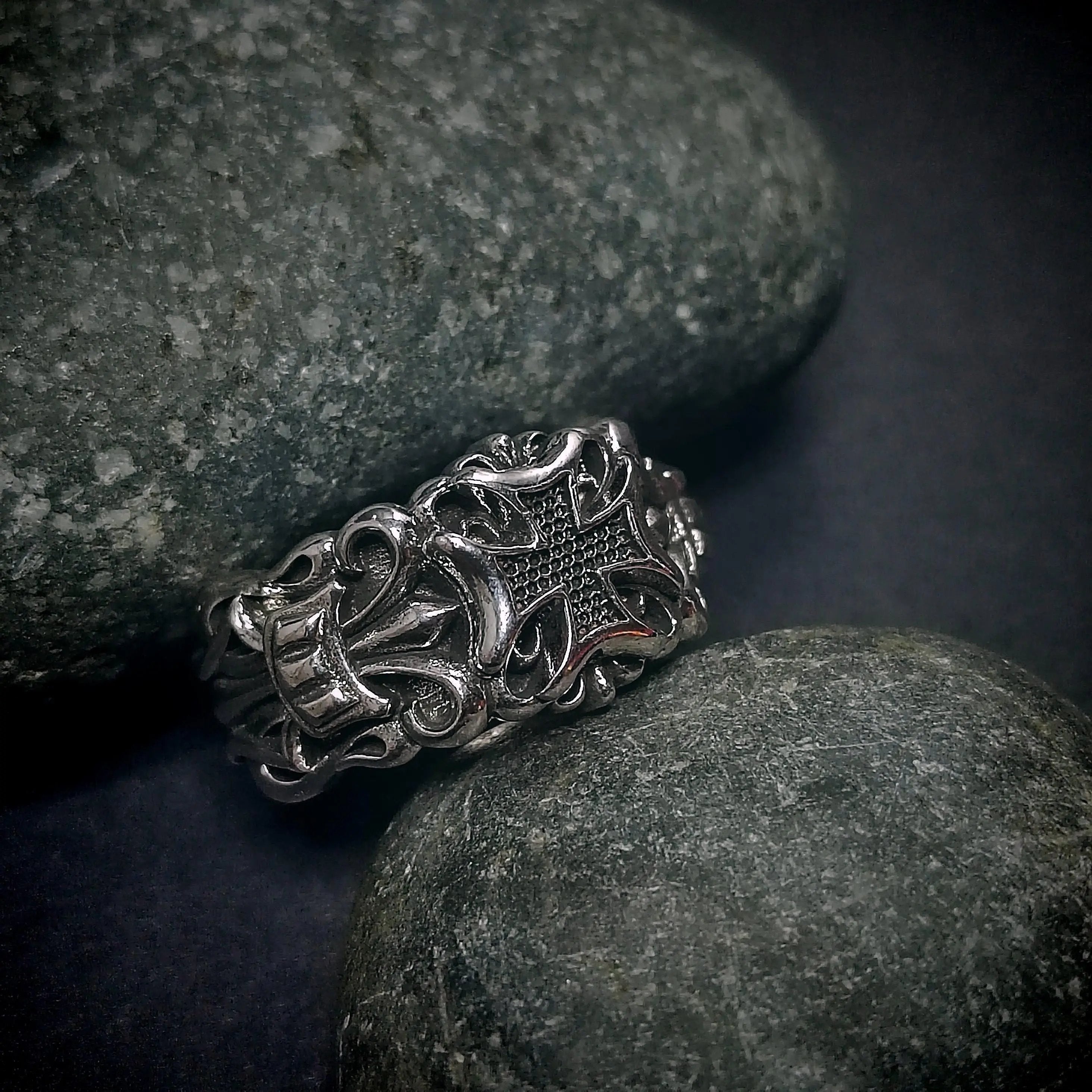 Silver ring with cross design on gray stones.
