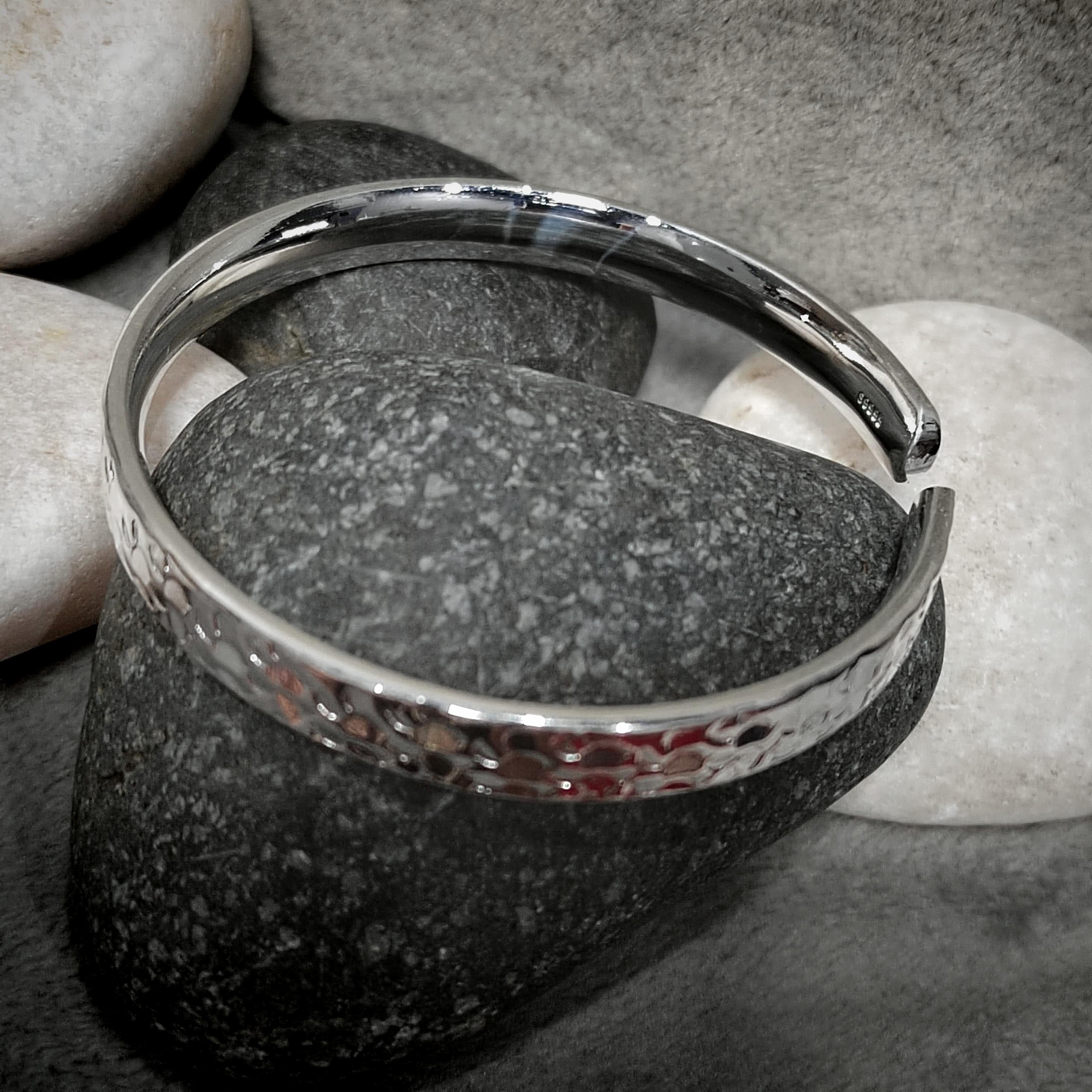Silver bracelet with textured design on a stone surface