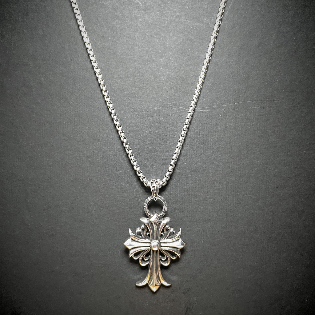Silver cross pendant necklace on a dark gray background