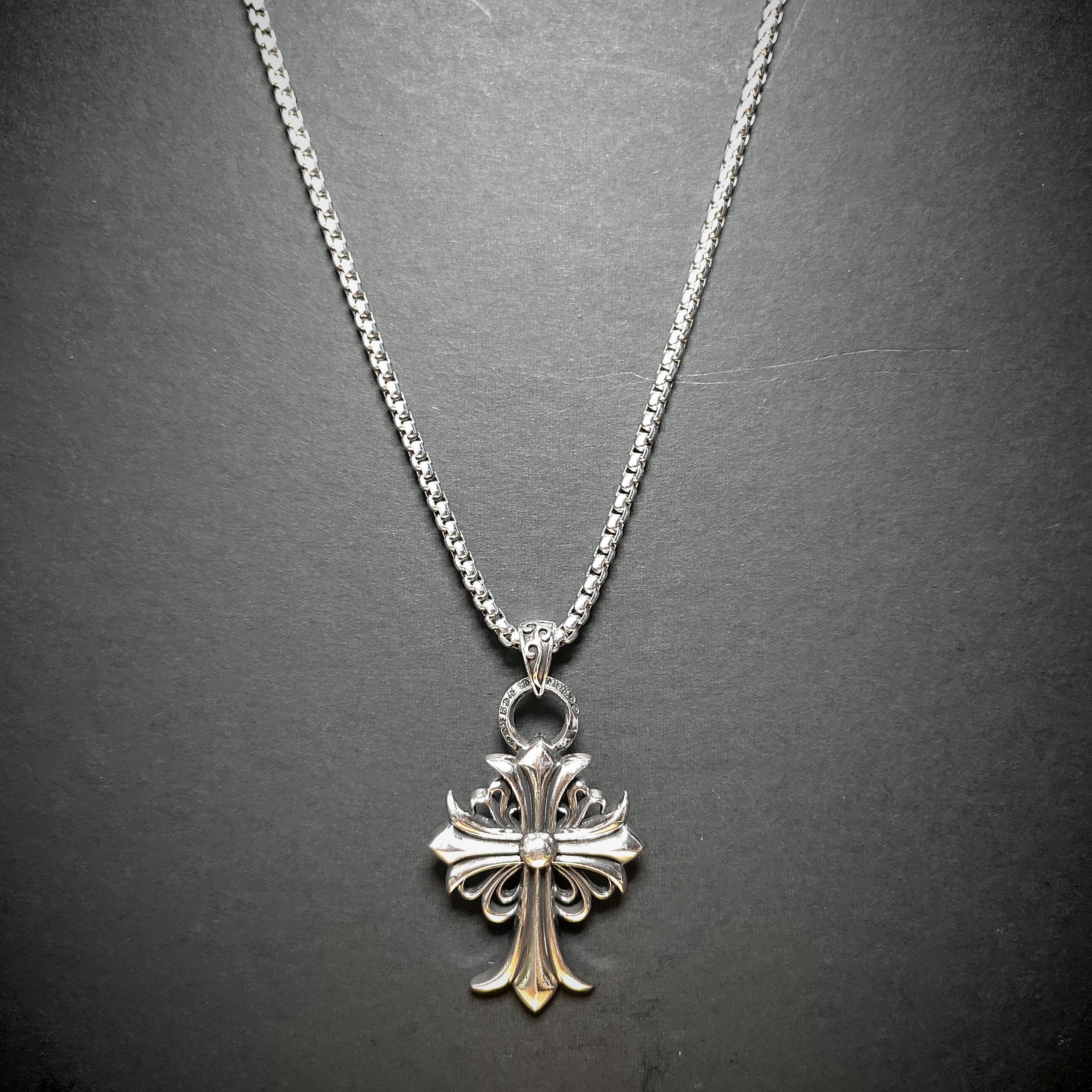 Silver cross pendant necklace on a dark gray background