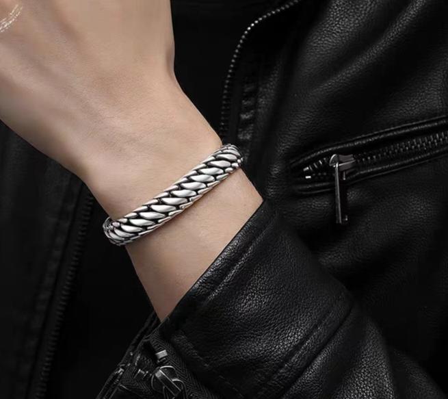 Silver braided bracelet on a wrist with a black leather jacket background