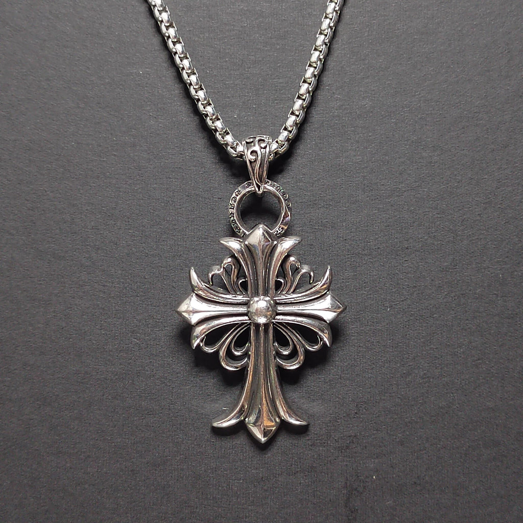 Silver cross pendant necklace on a dark gray background