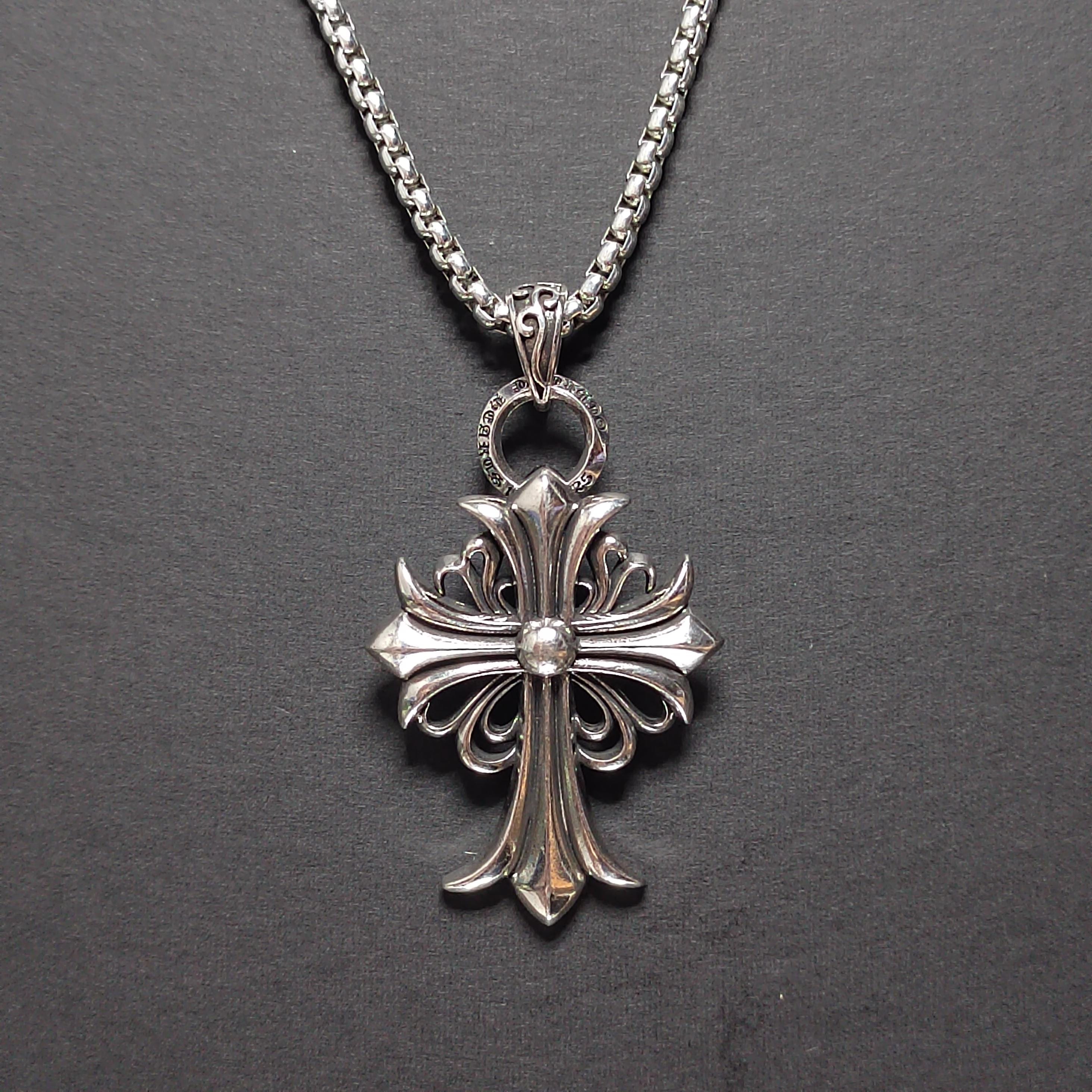Silver cross pendant necklace on a dark gray background