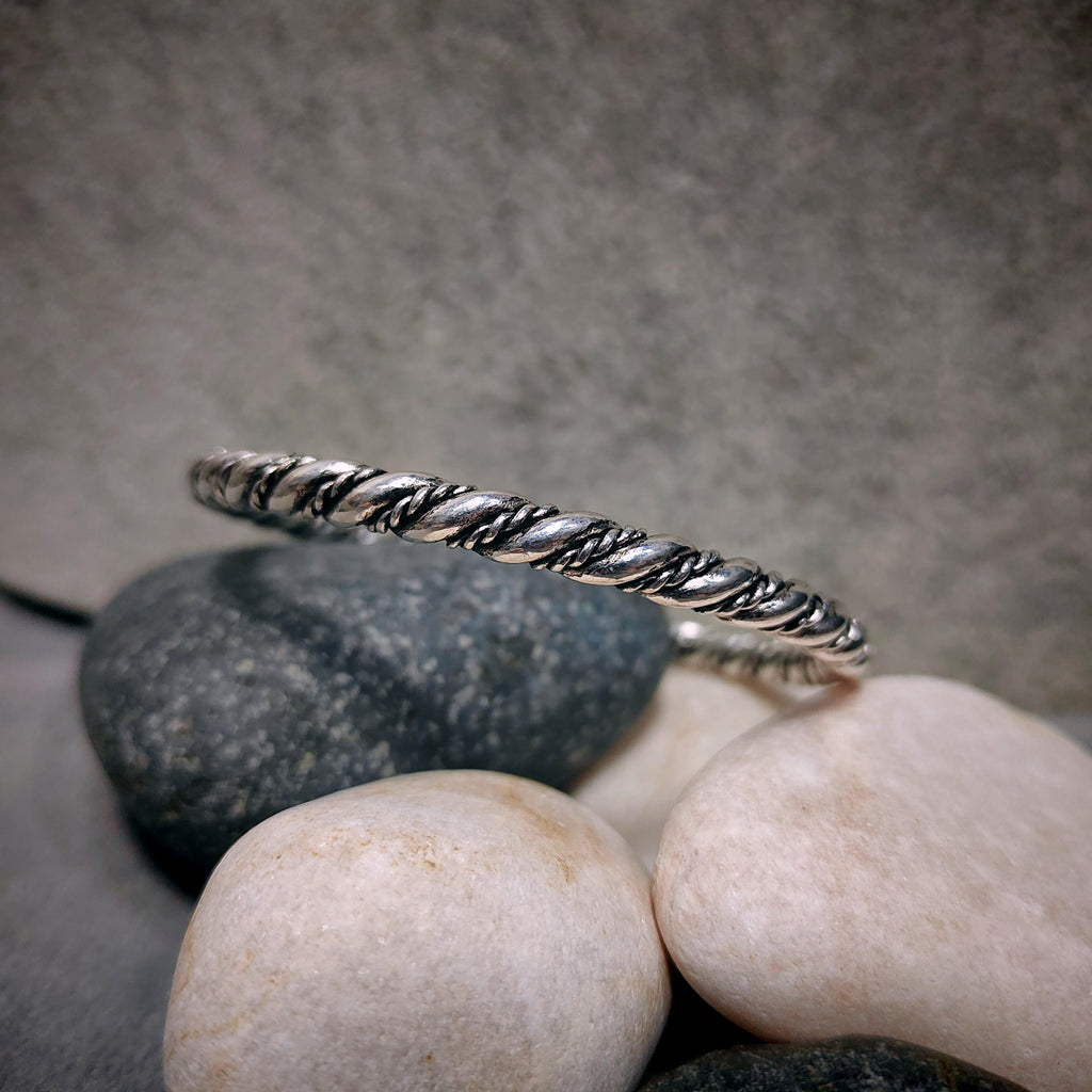 Silver bracelet on a stack of stones with a gray background