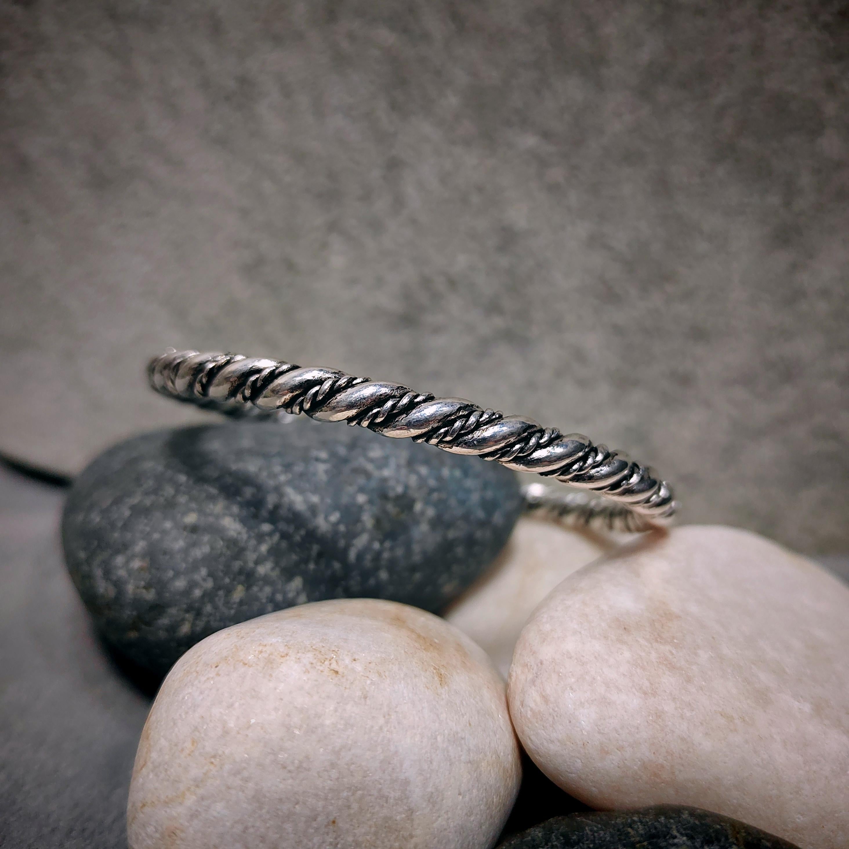 Silver bracelet on a stack of stones with a gray background