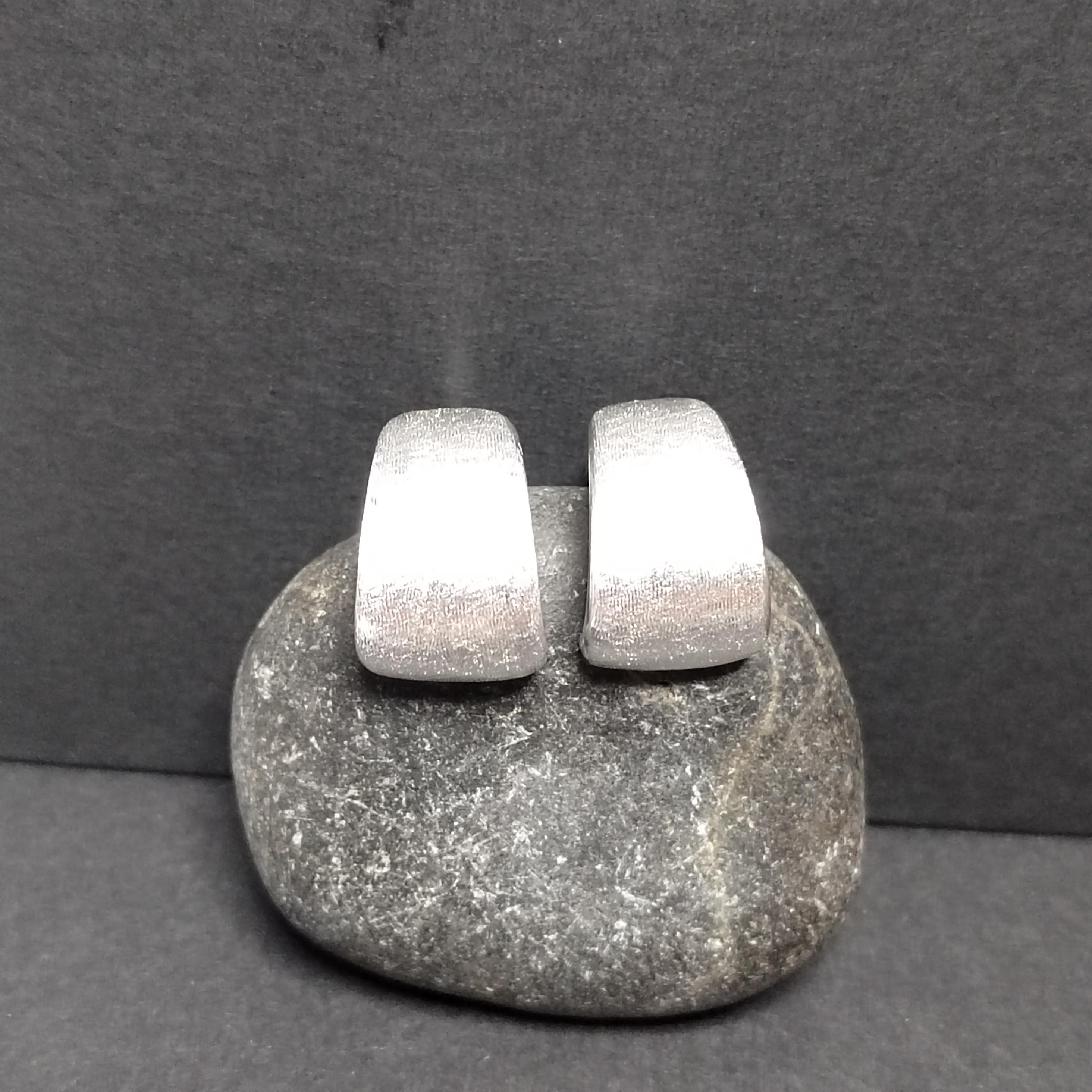 Pair of silver earrings on a gray stone with a dark gray background