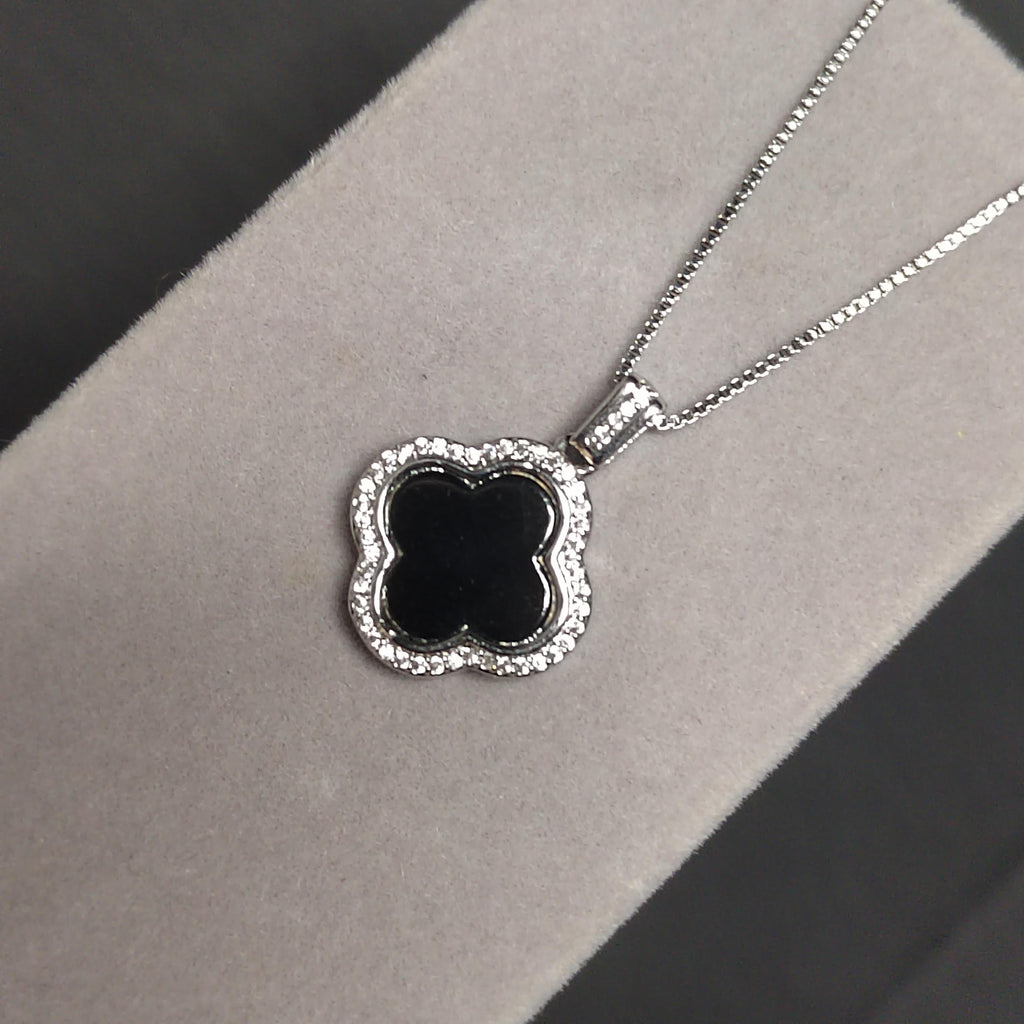 Silver necklace with a black floralclover pendant on a gray background
