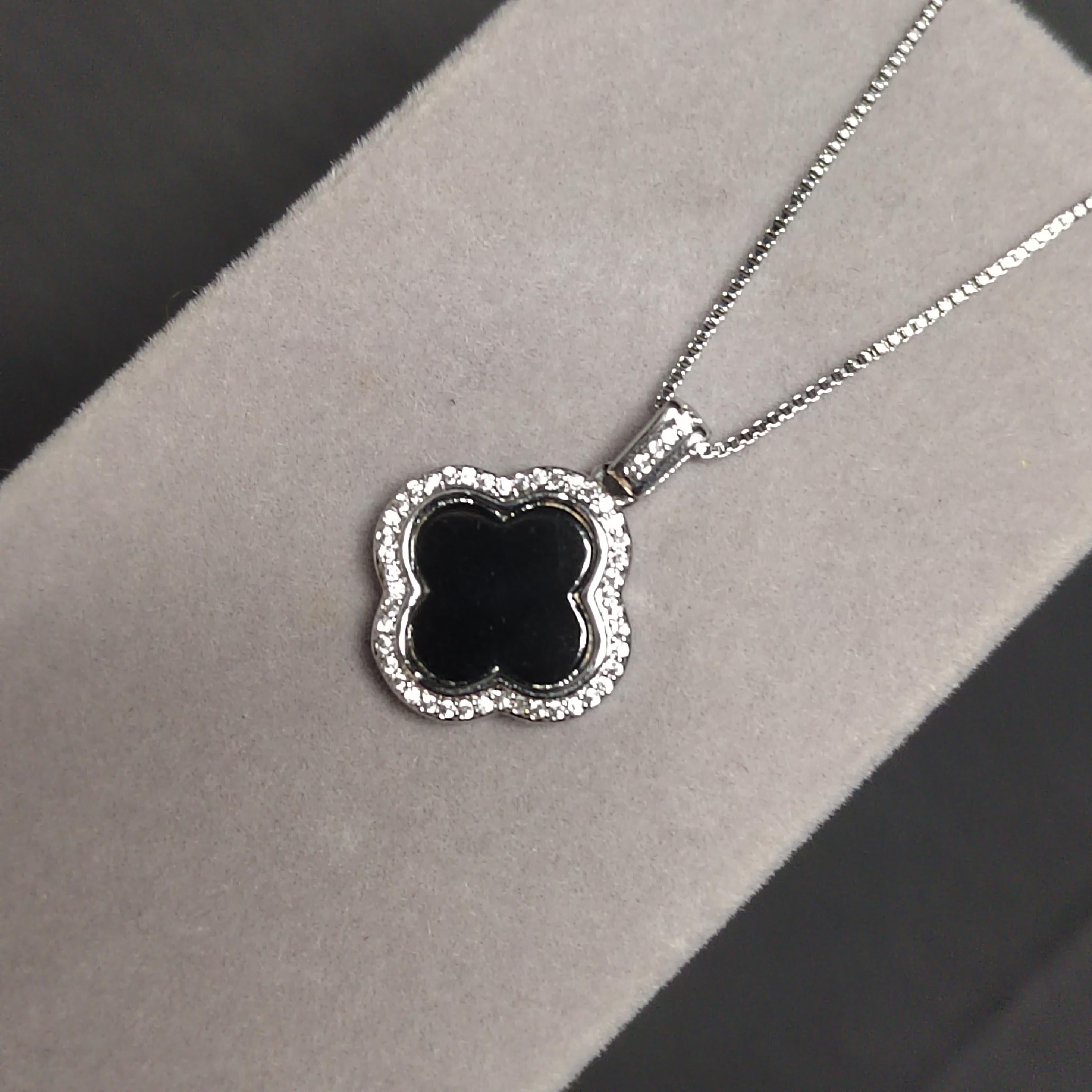Silver necklace with a black floralclover pendant on a gray background