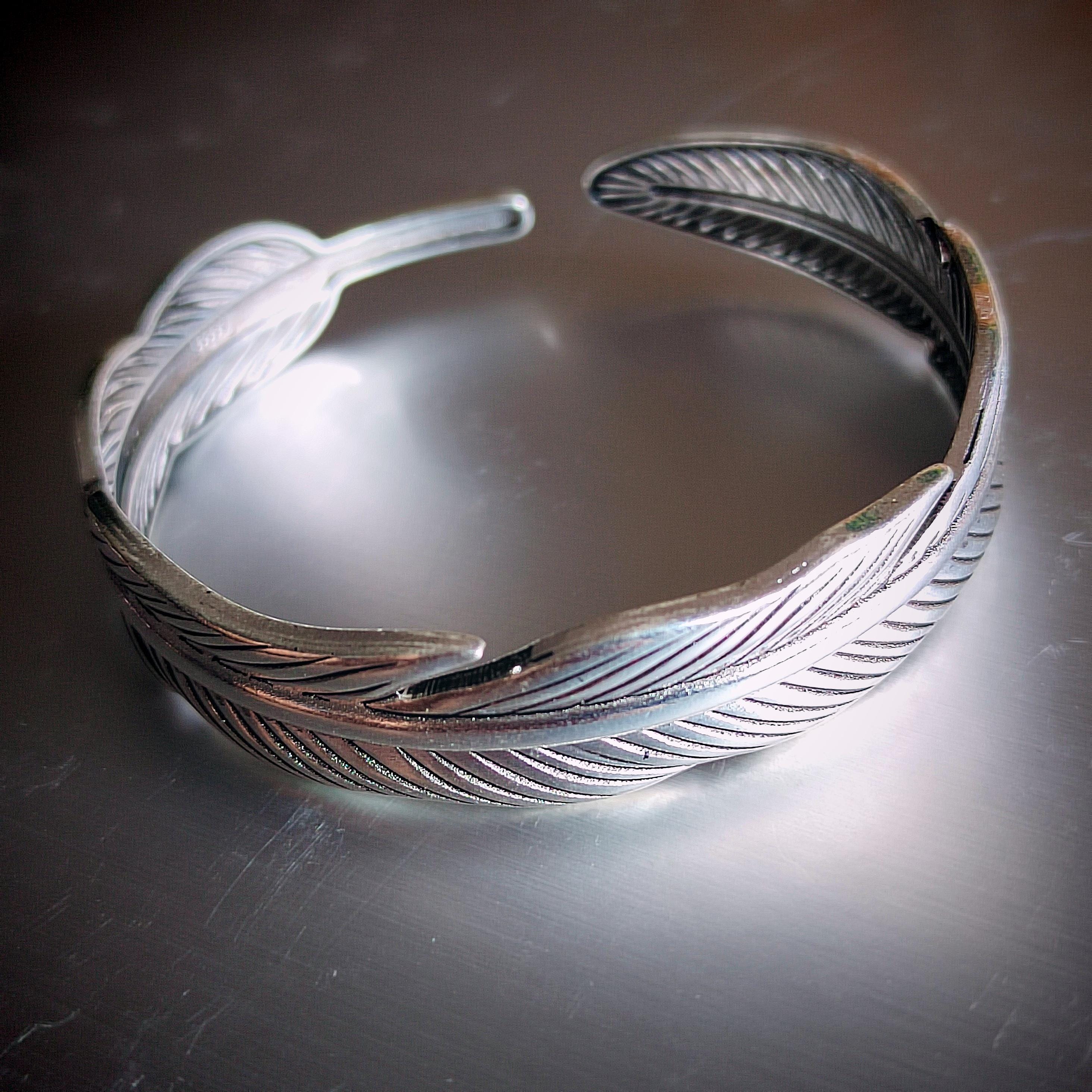 Silver feathered bracelet on a reflective surface
