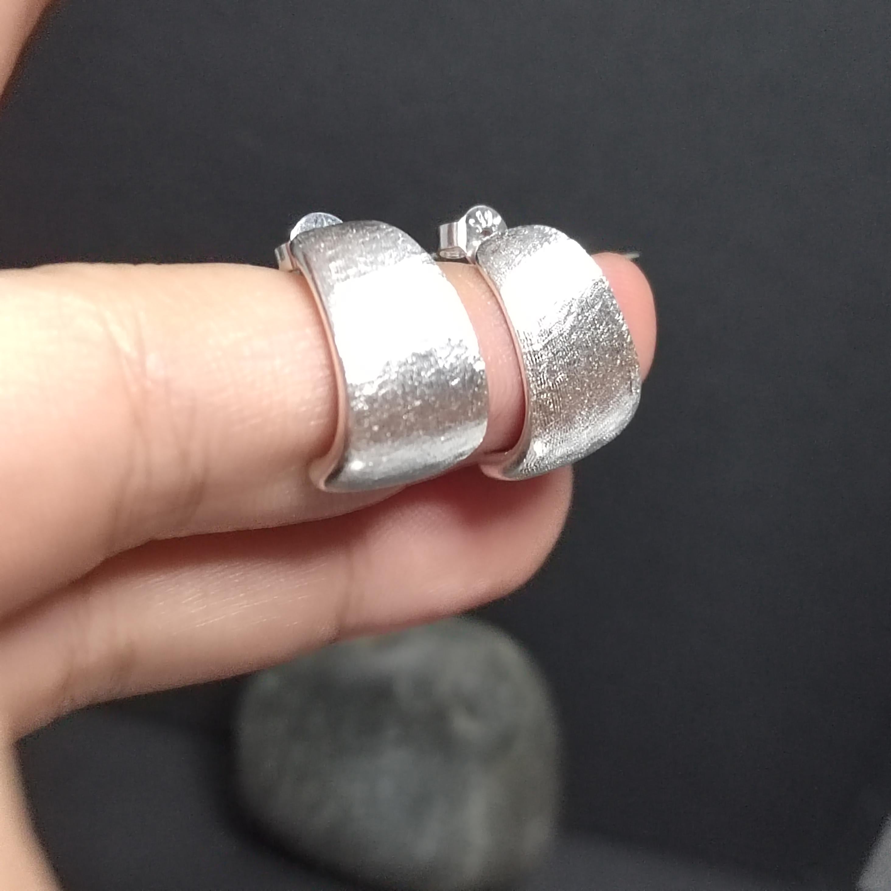 Silver ring on a finger against a dark background