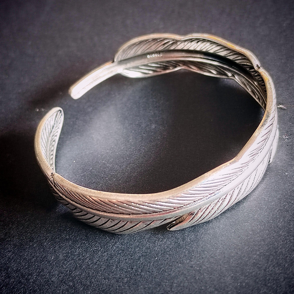 Silver feathered bracelet on a dark surface