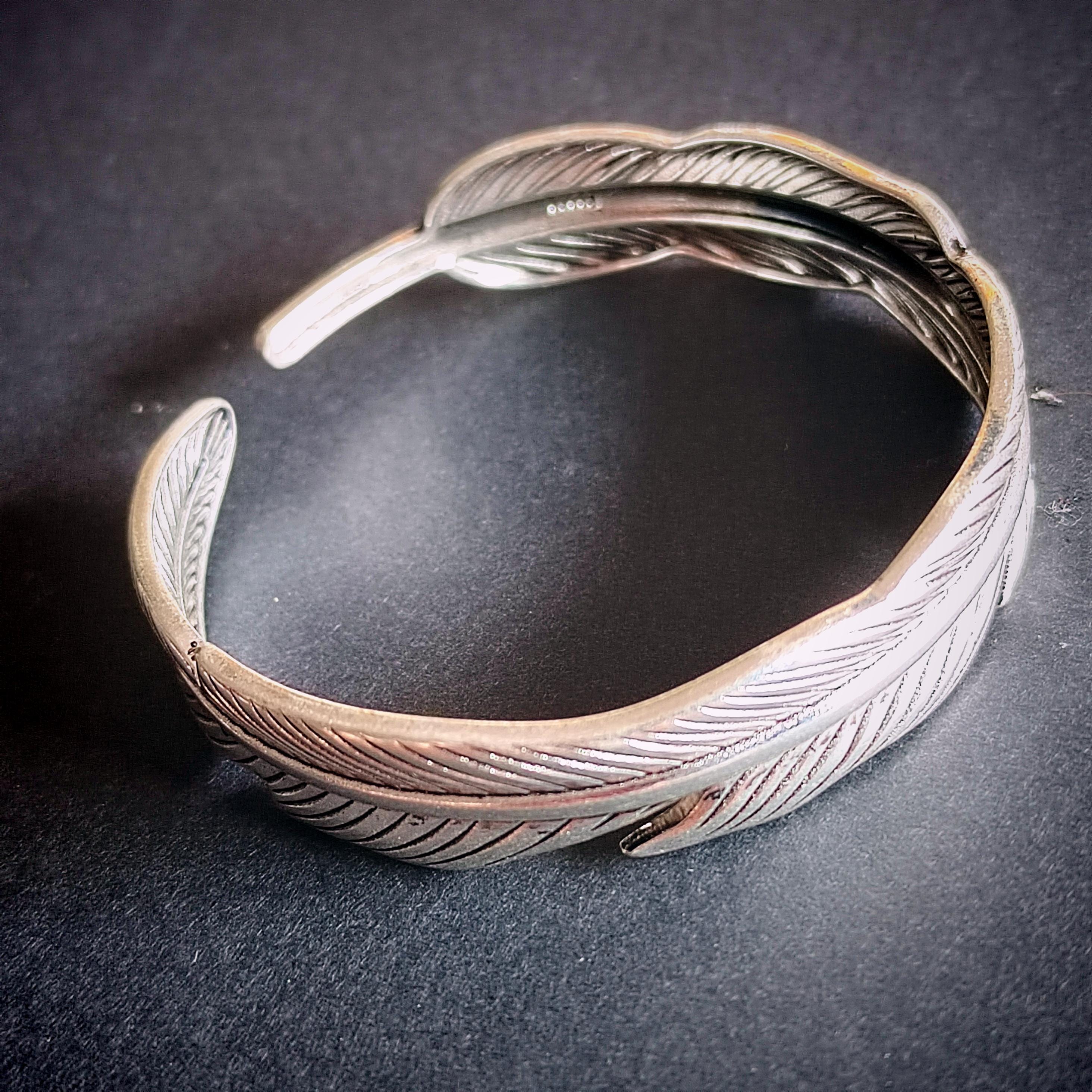 Silver feathered bracelet on a dark surface