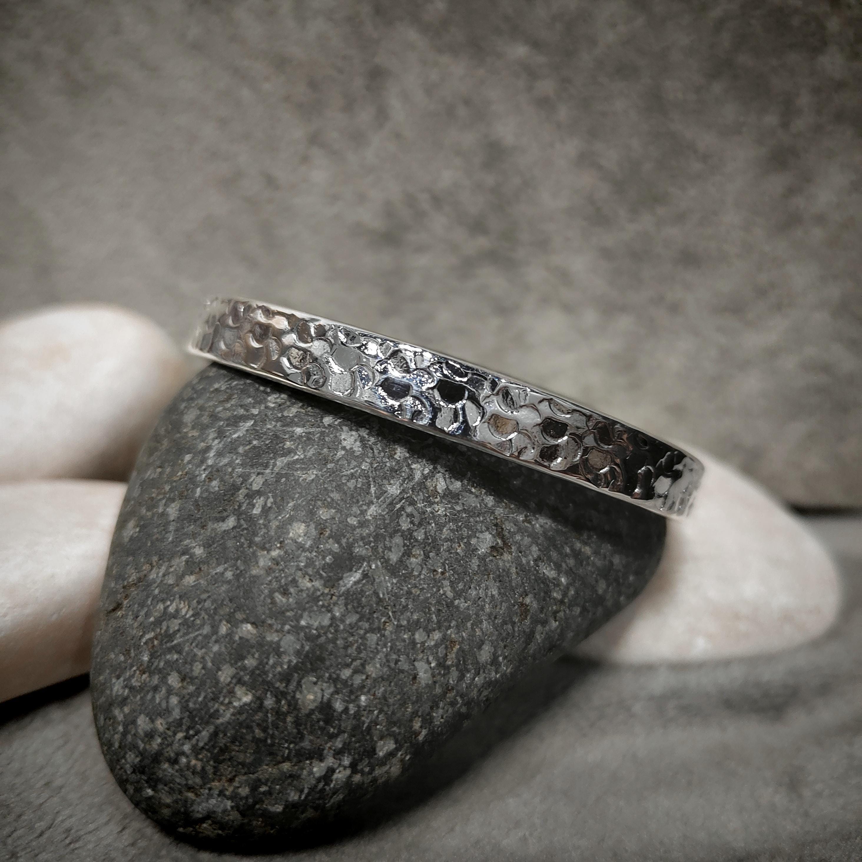 Silver bracelet with a textured pattern on a gray stone surface