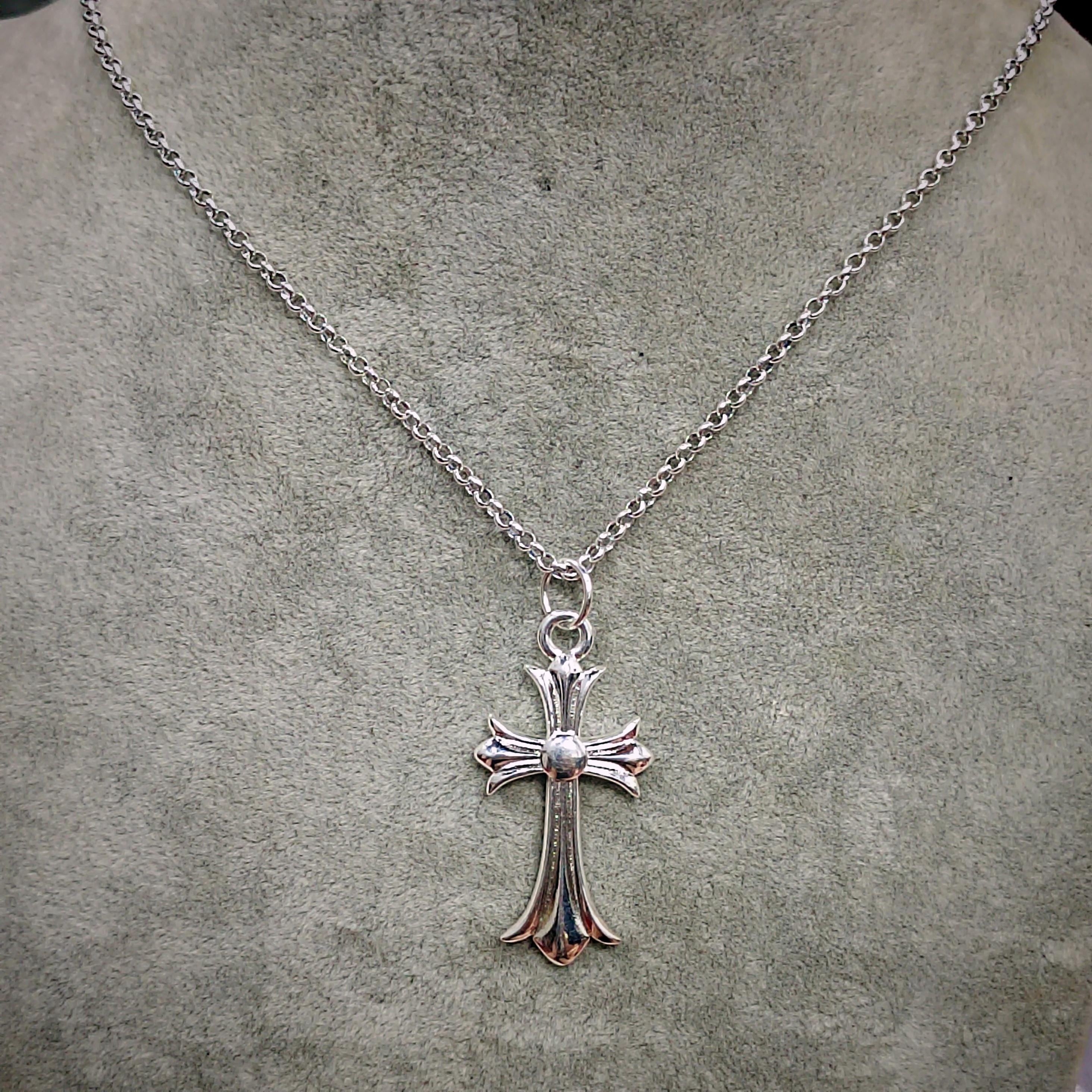 Silver cross necklace on a gray surface