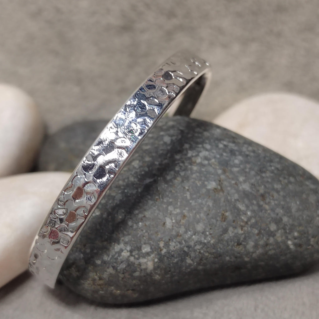 Silver textured ring on a stone surface