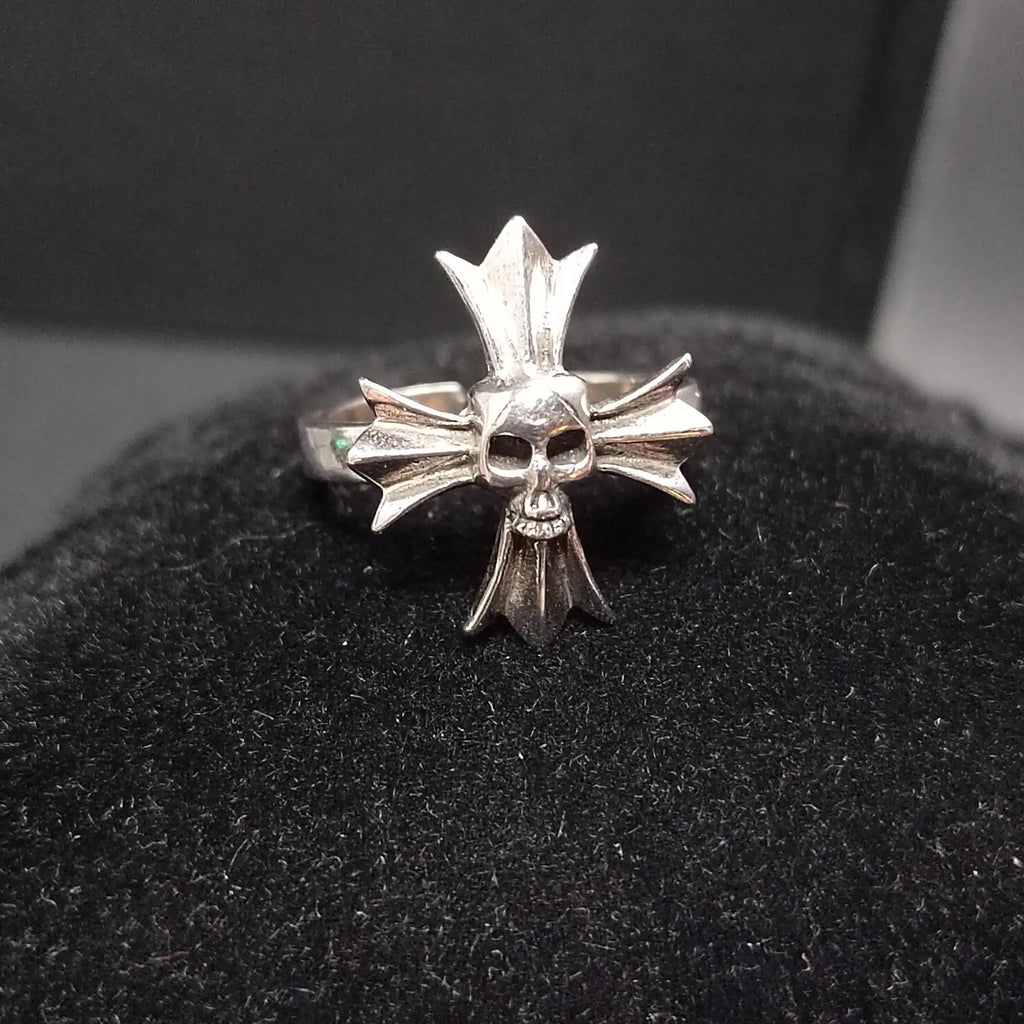 Silver ring with skull and crossbones design on a black cushion