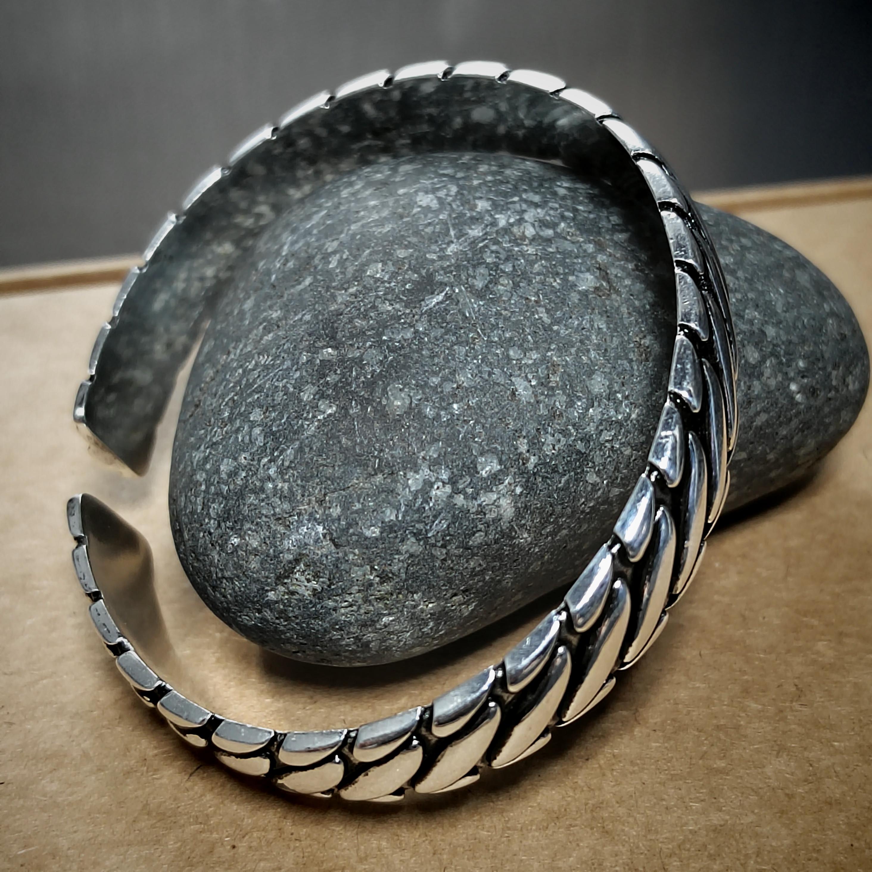 Silver bracelet on a gray stone with a brown surface
