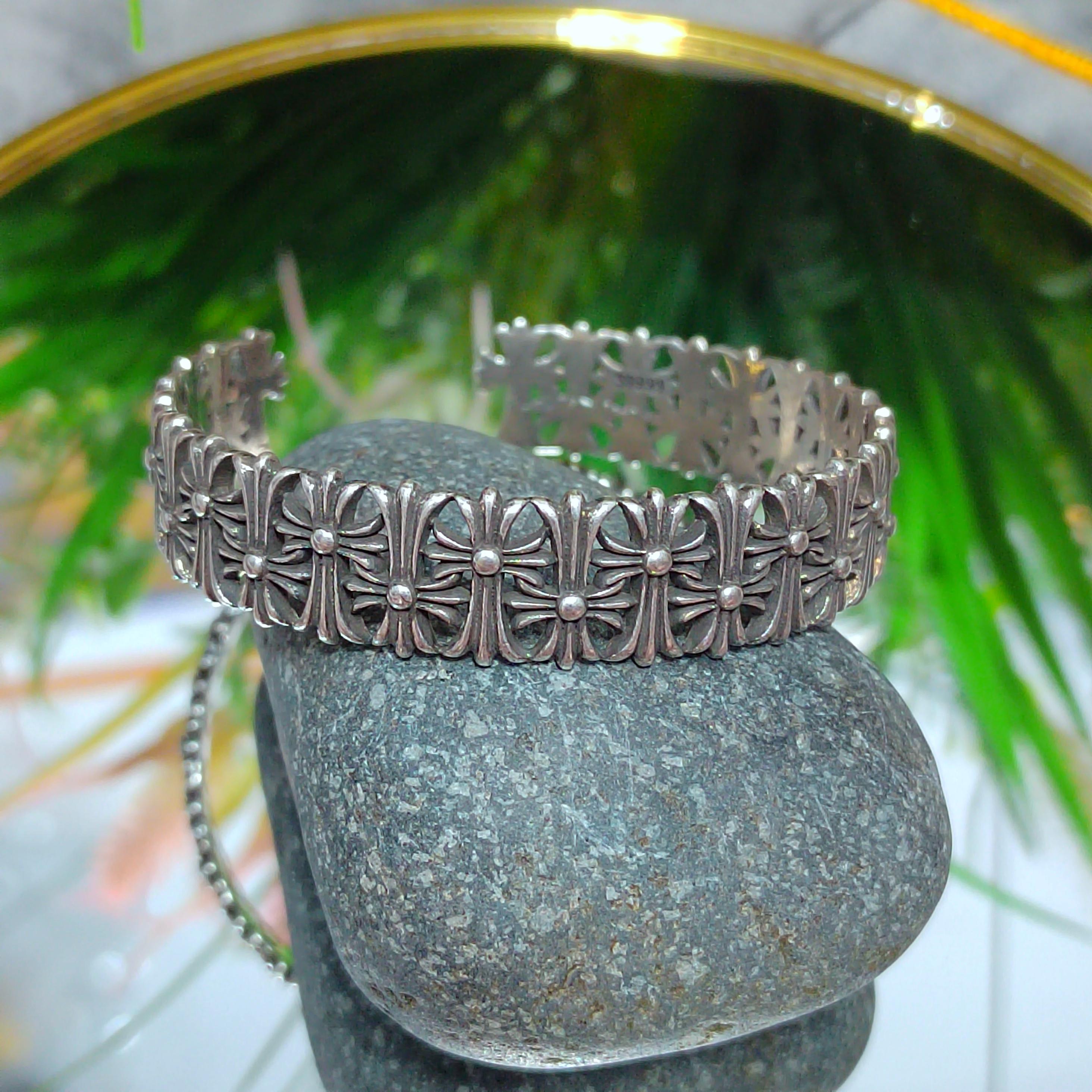 Silver bracelet on a stone with green foliage in the background