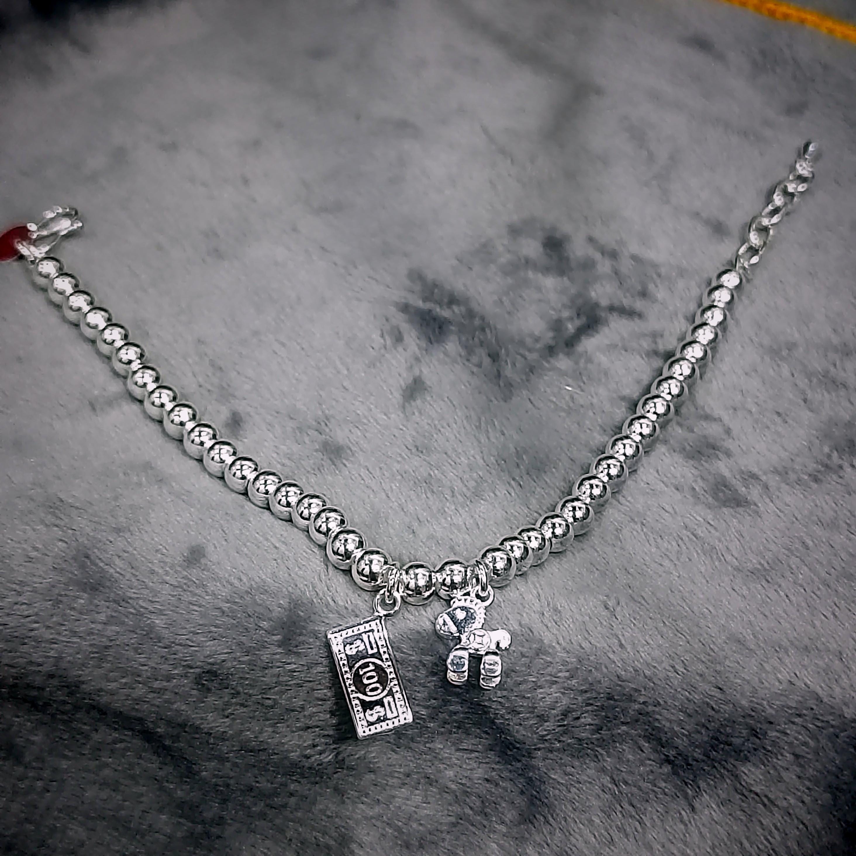 Silver bracelet with a teddy bear charm on a textured gray surface