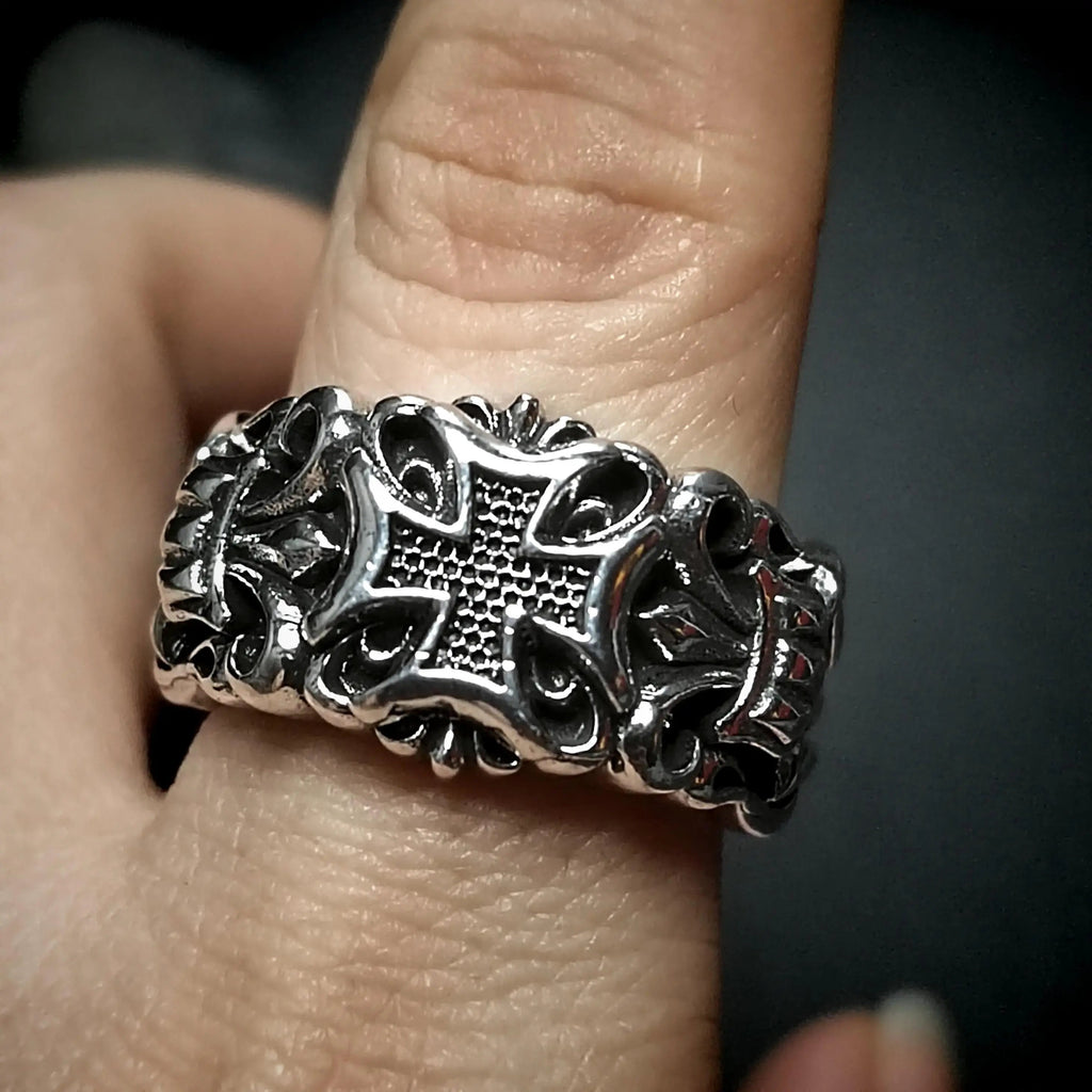 Silver ring with cross design on finger.