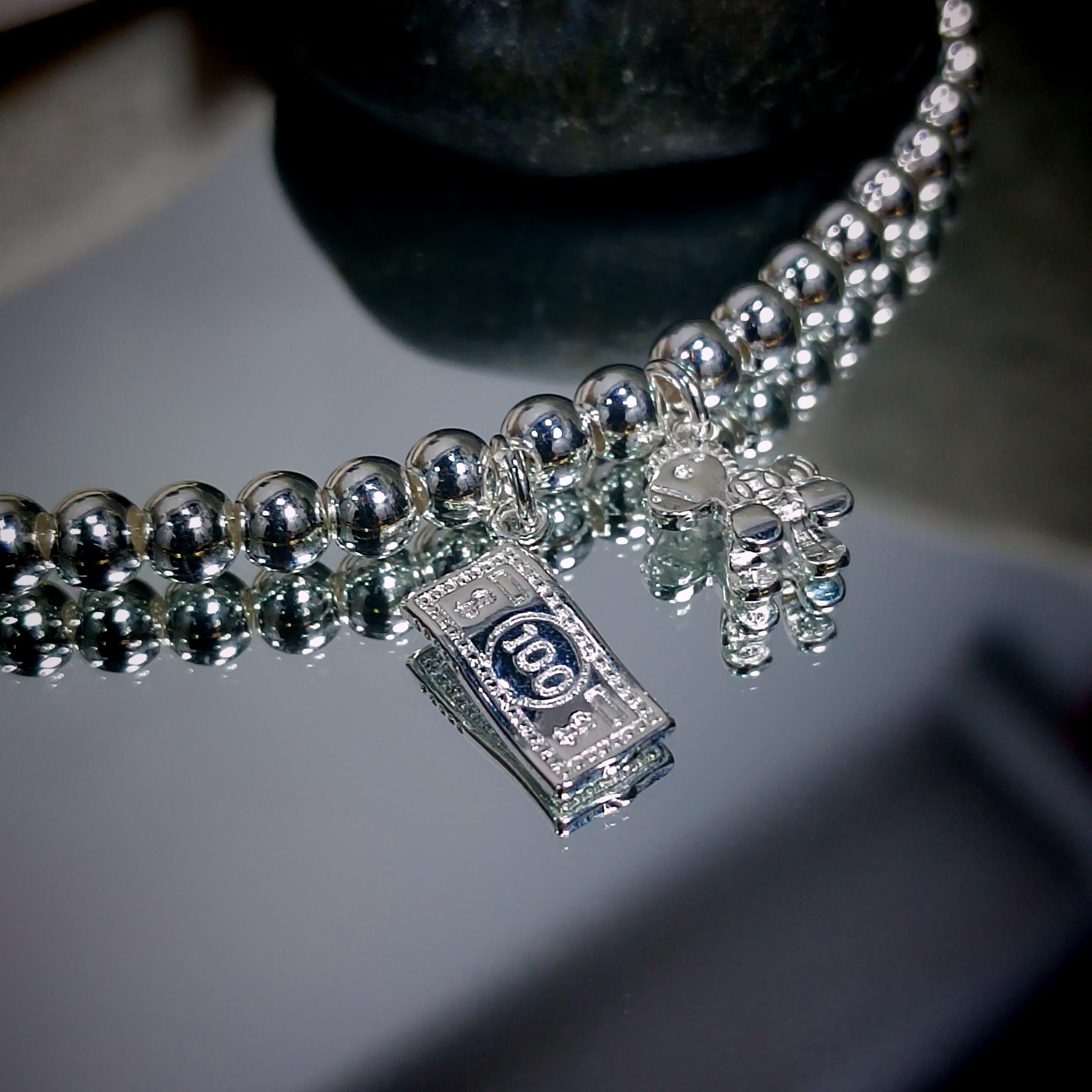 Silver beaded necklace with a '100' pendant on a reflective surface