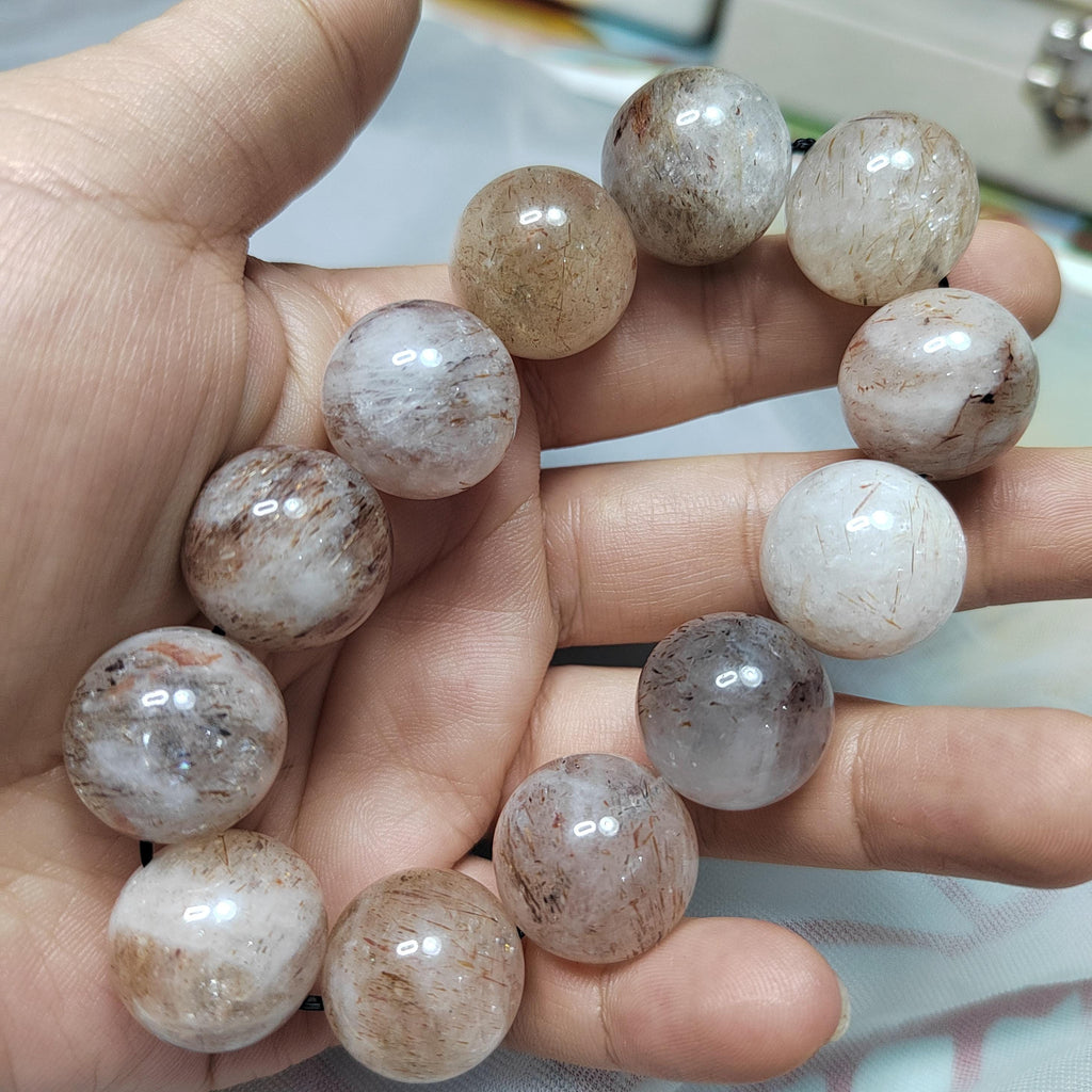 Hand holding a bracelet with round, marbled beads.