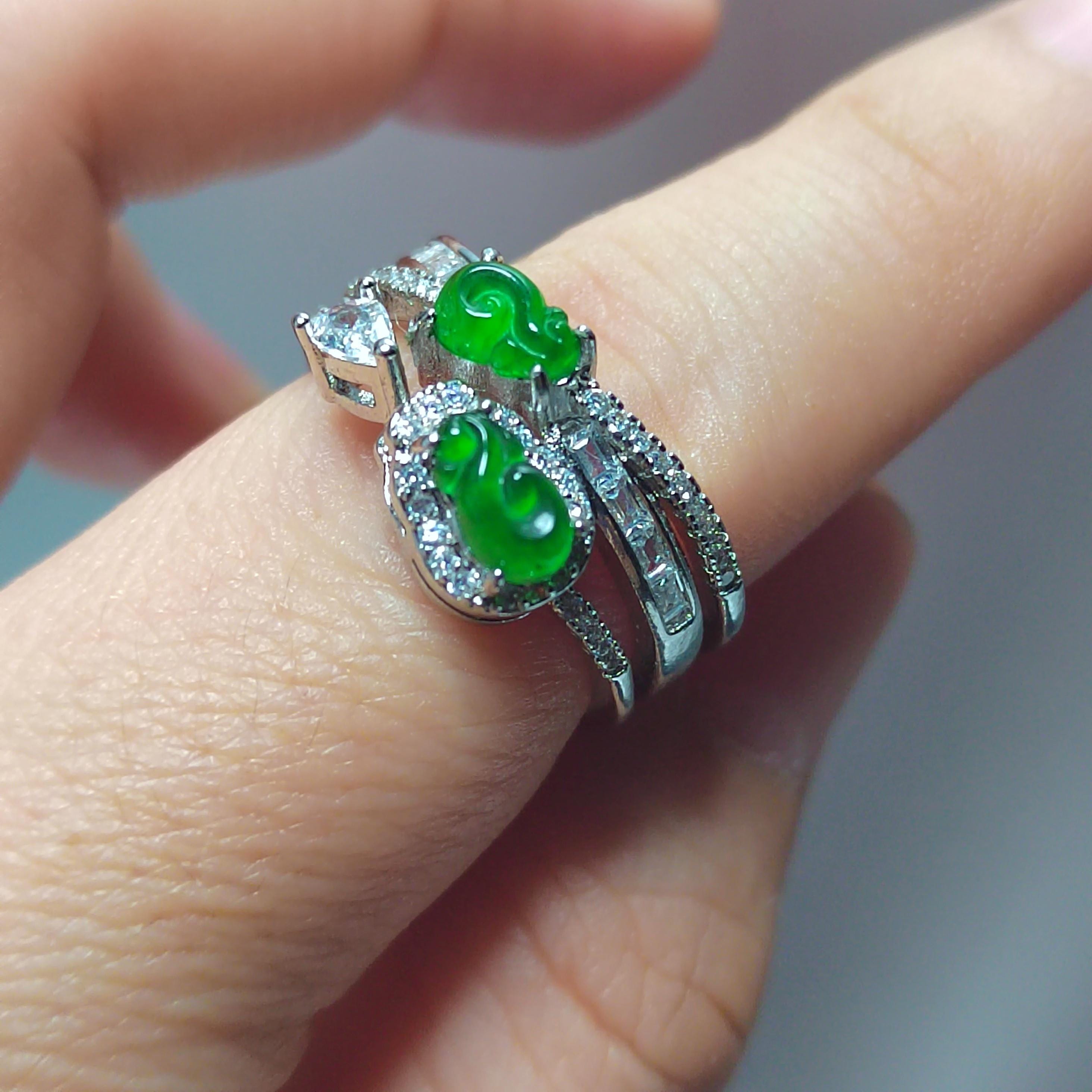 Two green gemstone rings on a finger with a blurred background