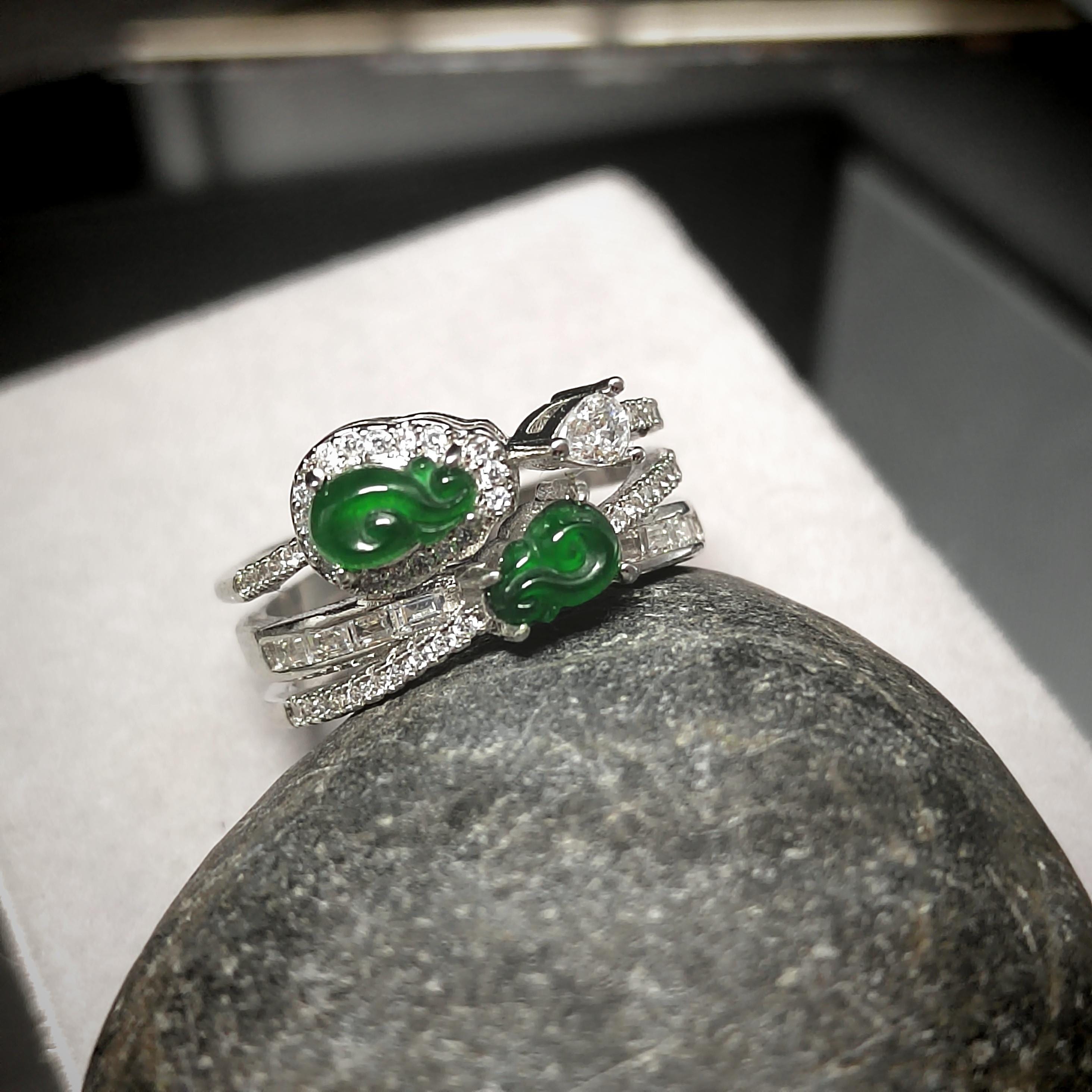 Silver ring with green gemstones on a stone surface