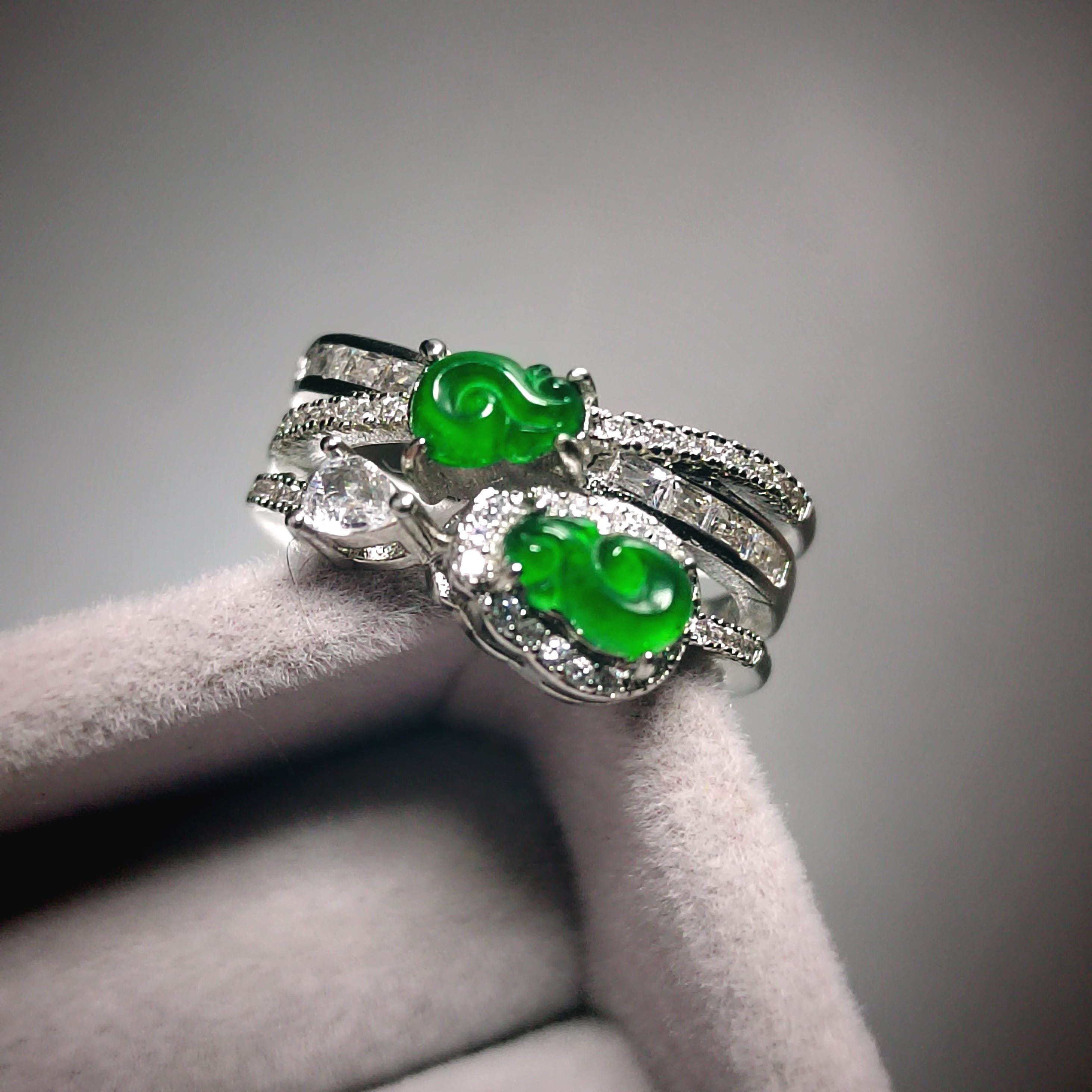 Silver ring with green gemstones on a gray background