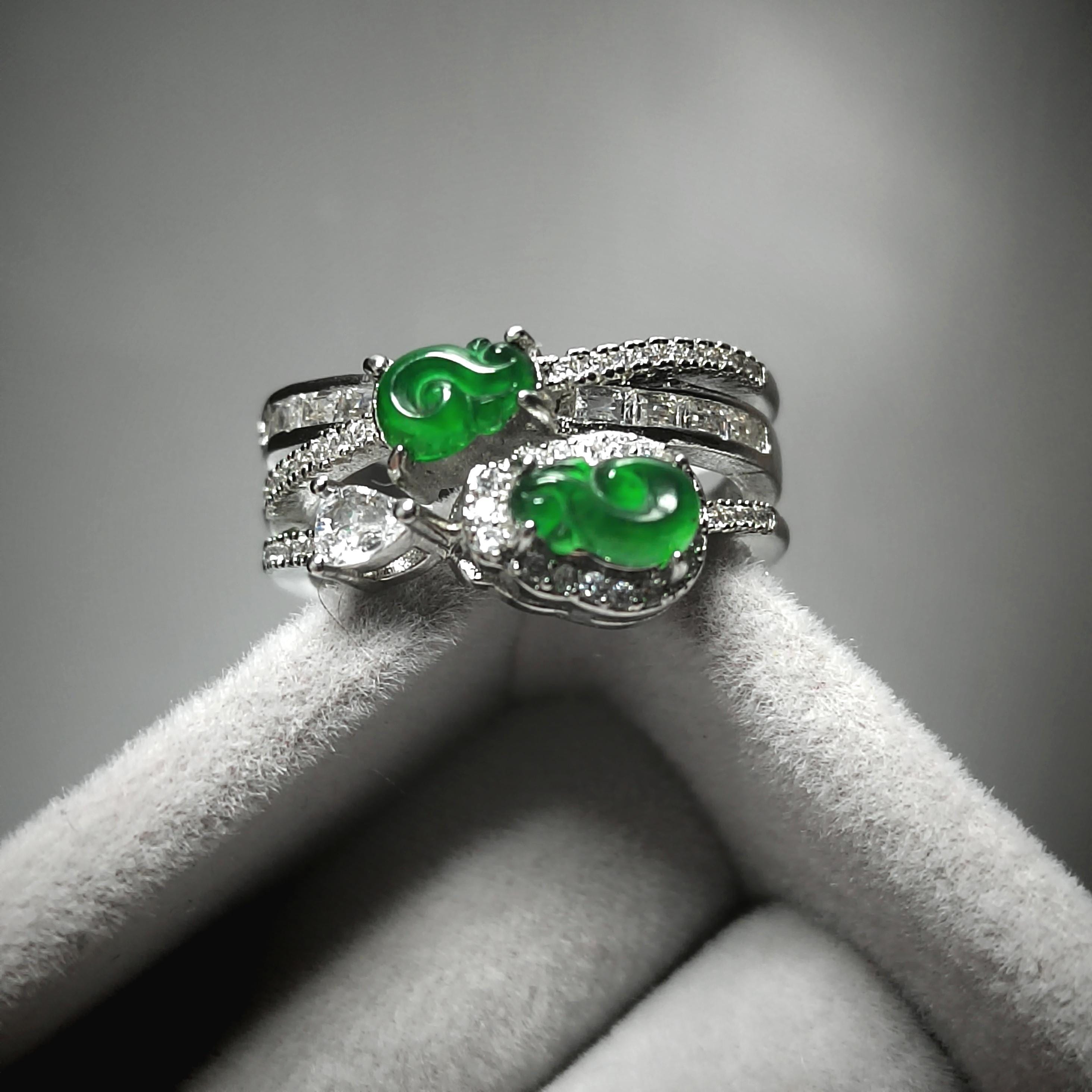 Silver ring with green gemstones on a gray background