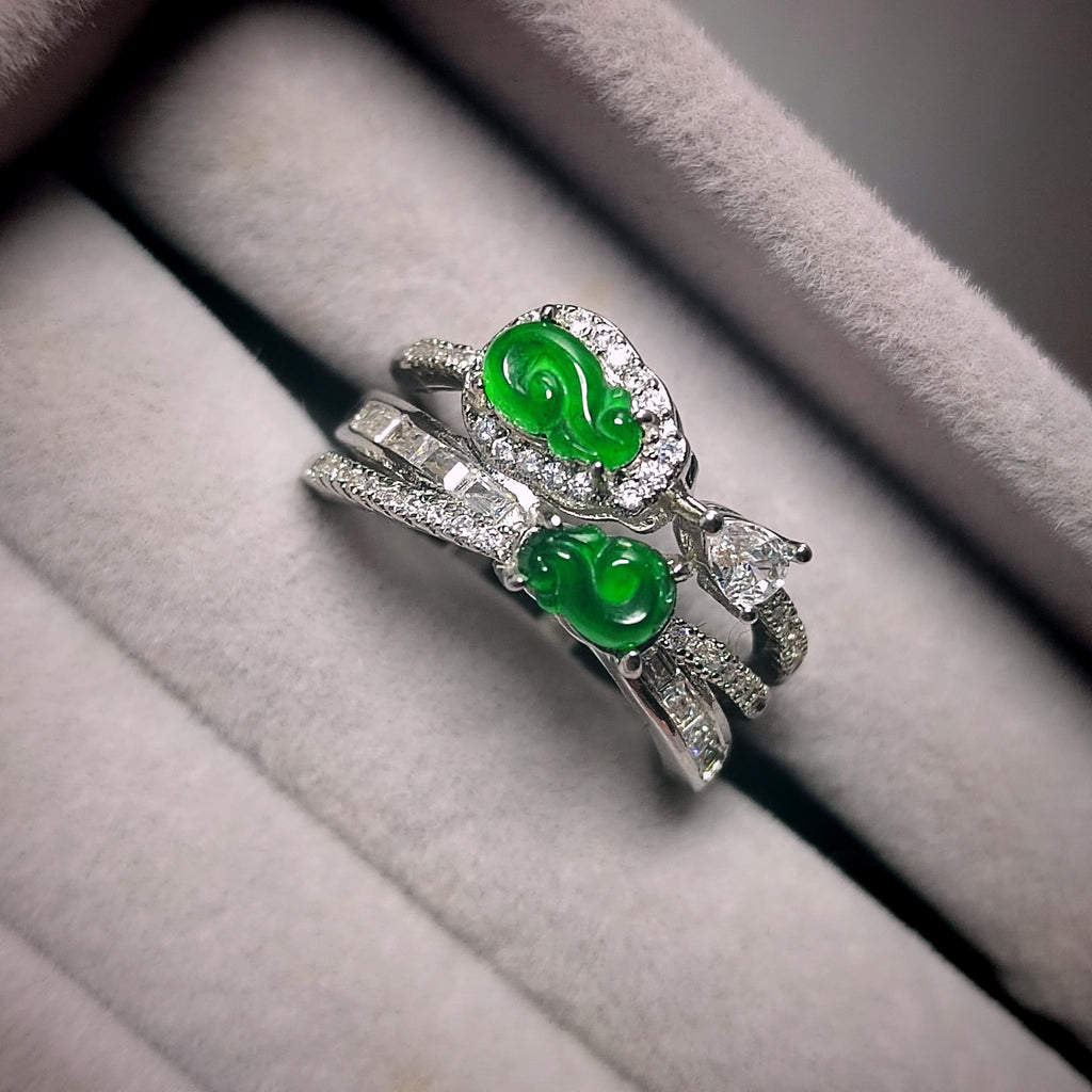 Silver ring with green gemstones on a soft gray surface