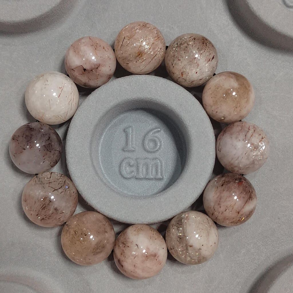 Gray circular object with '16 cm' marking surrounded by round stones on a gray background