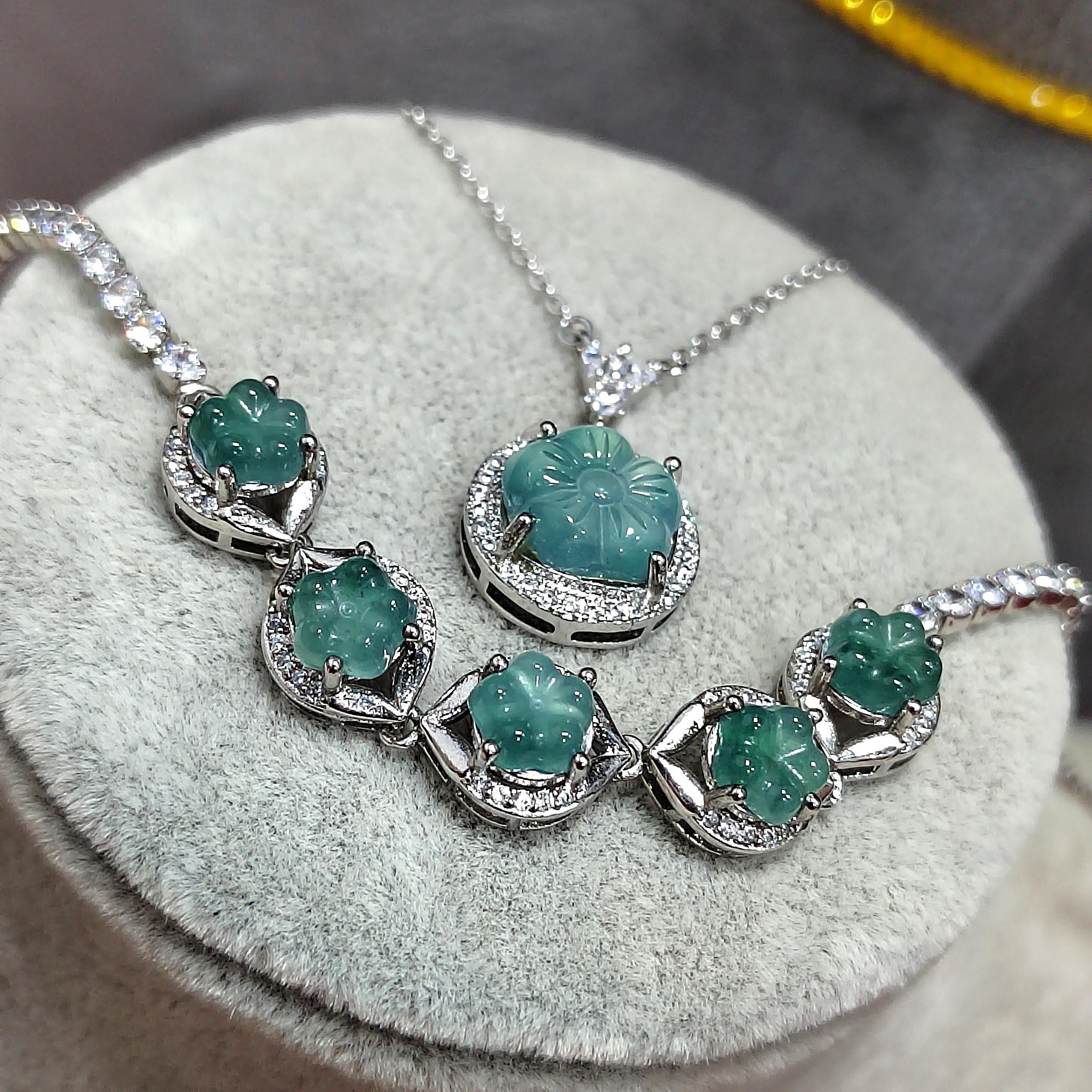 Jewelry set with emerald green stones on a round gray surface