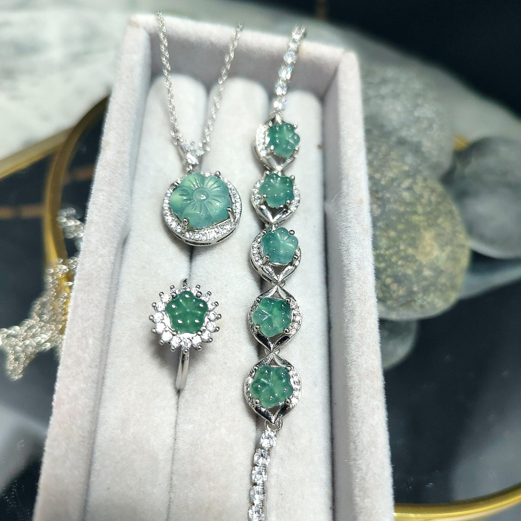 Jewelry set with emerald green stones on a white cushion