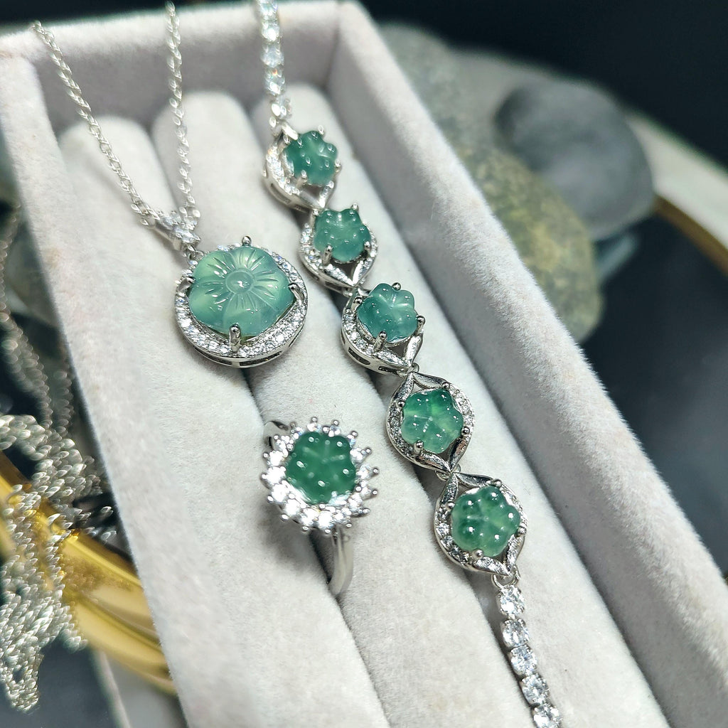 Silver necklace with green gemstones on a white cushion