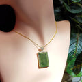 Green jadeite pendant necklace on a mannequin with green leaves in the background