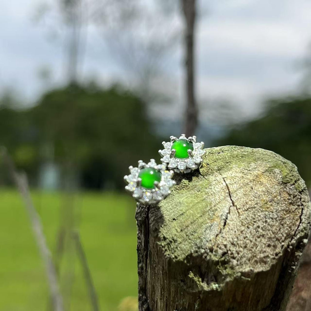Pair of earrings with green gemstones on a wooden post outdoors