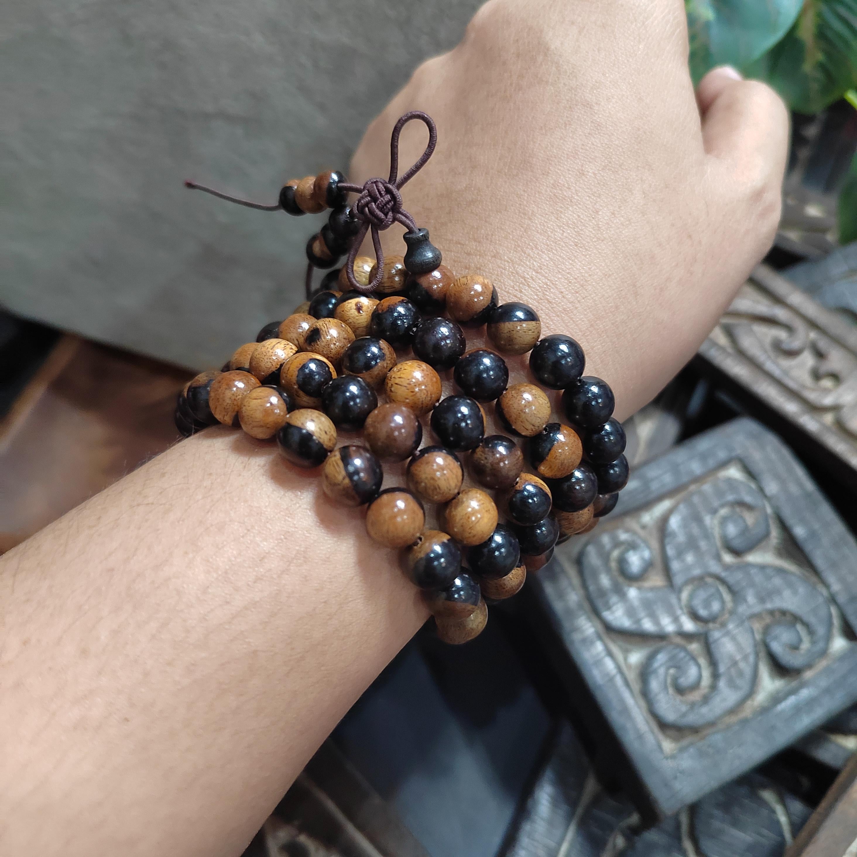 Close-up of a wrist wearing a bracelet with black and brown beads, with a decorative box in the background.