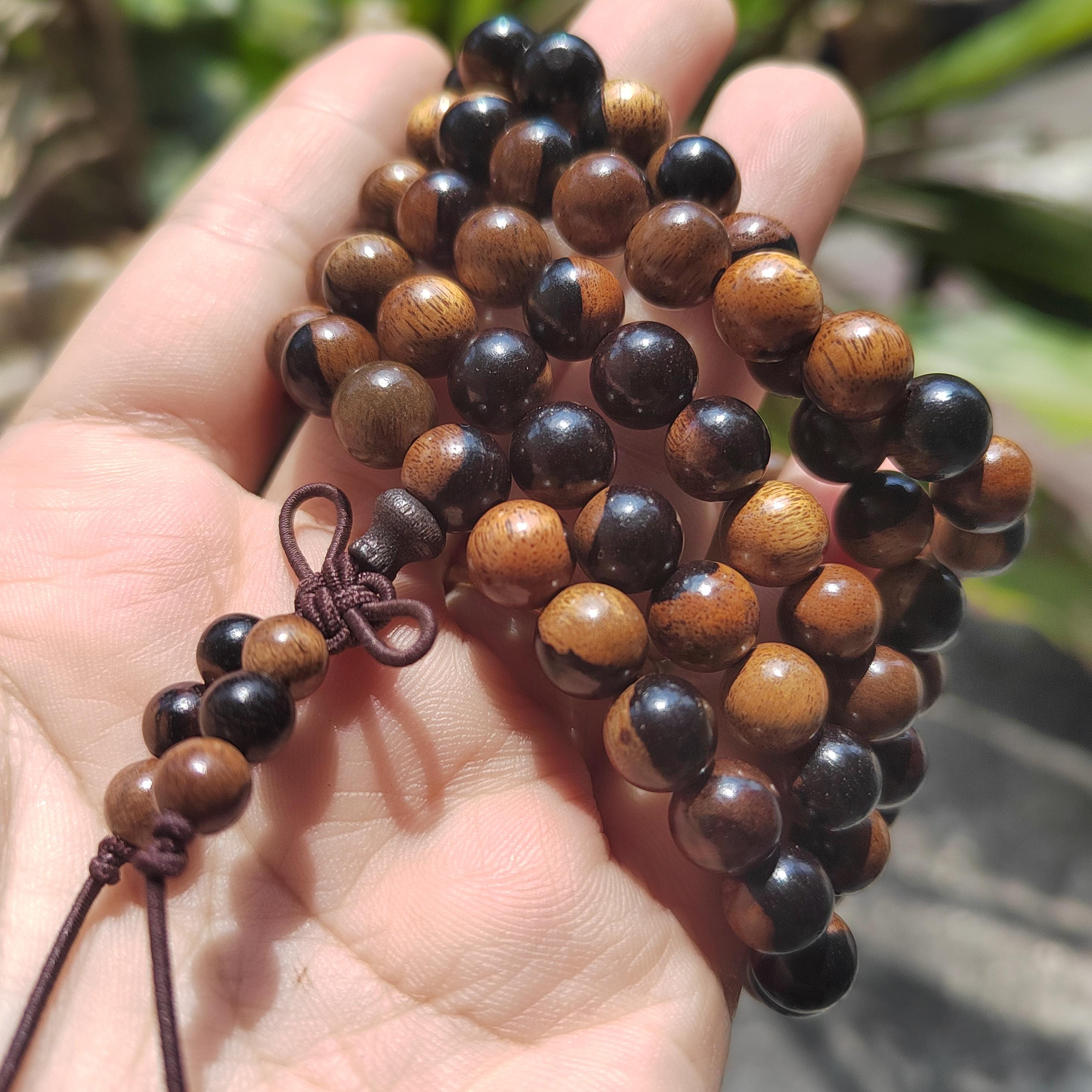 Wooden beaded necklace held in a hand with a blurred natural background