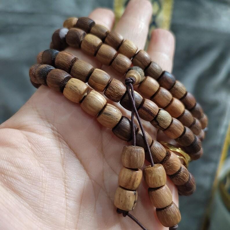 Wooden beaded bracelet held in a hand with a blurred natural background