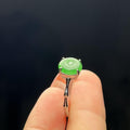 Green jade ring on a finger against a dark background