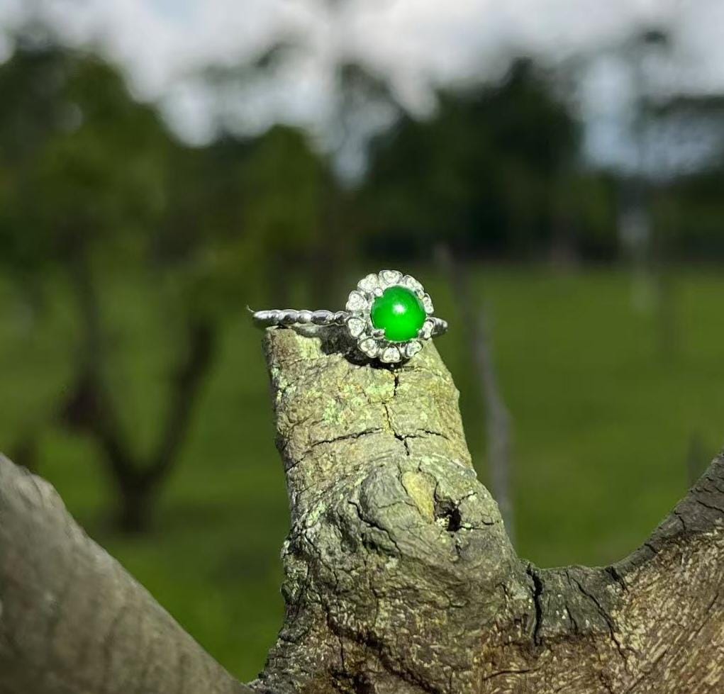 Ring with a green gemstone on a tree stump with a blurred natural background