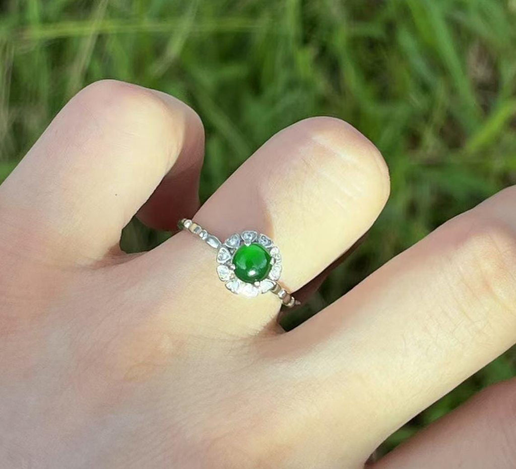 Ring with a green gemstone on a finger against a blurred green background