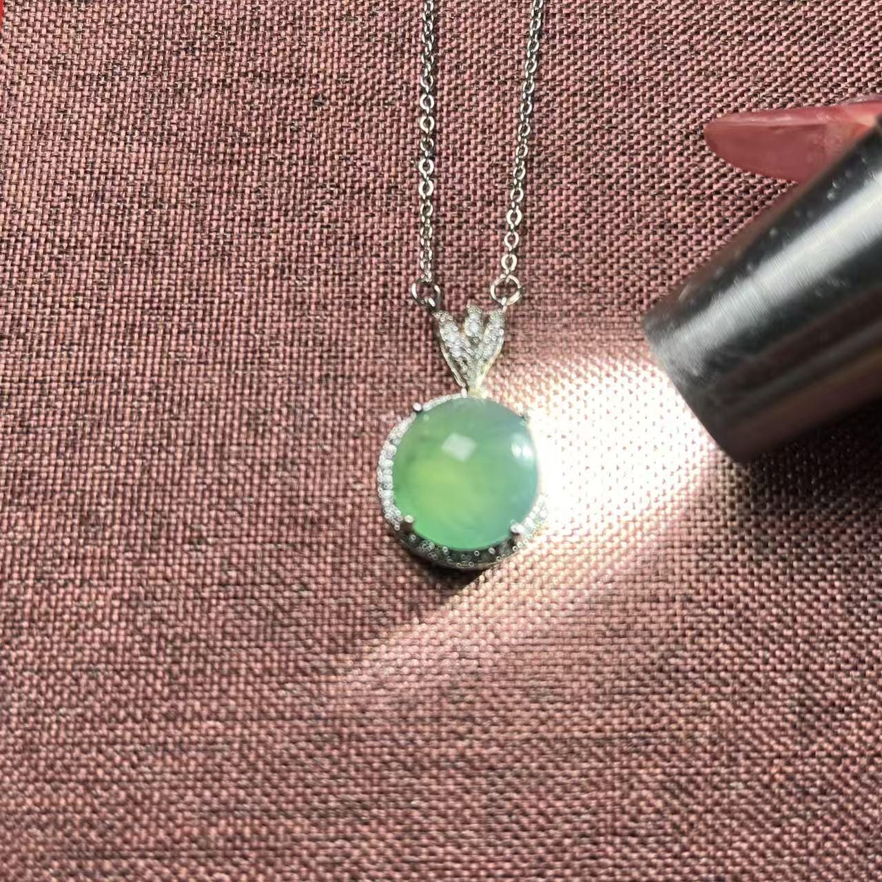 Necklace with a green pendant on a textured brown surface