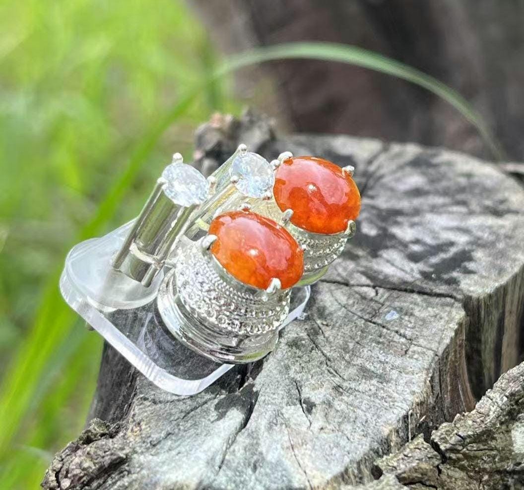 Silver ring with red stones on a wooden stump